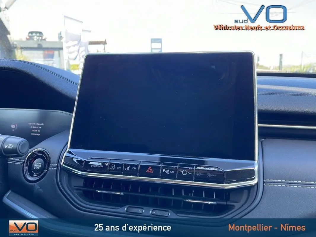 Vue rapprochée de l'écran tactile et des commandes du tableau de bord du Jeep Compass blanc 2024 en intérieur.