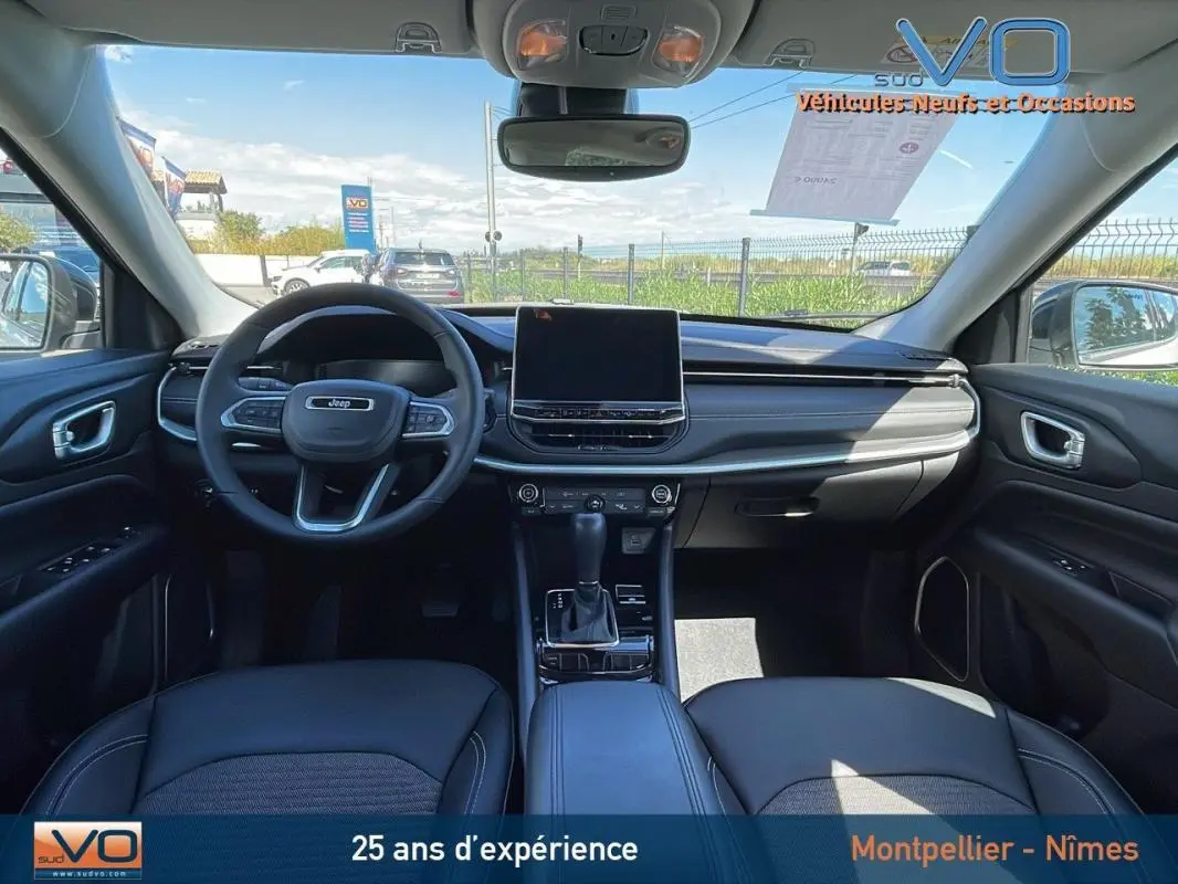 Intérieur du Jeep Compass 2024 blanc, vue avant du tableau de bord avec écran tactile et volant multifonction.