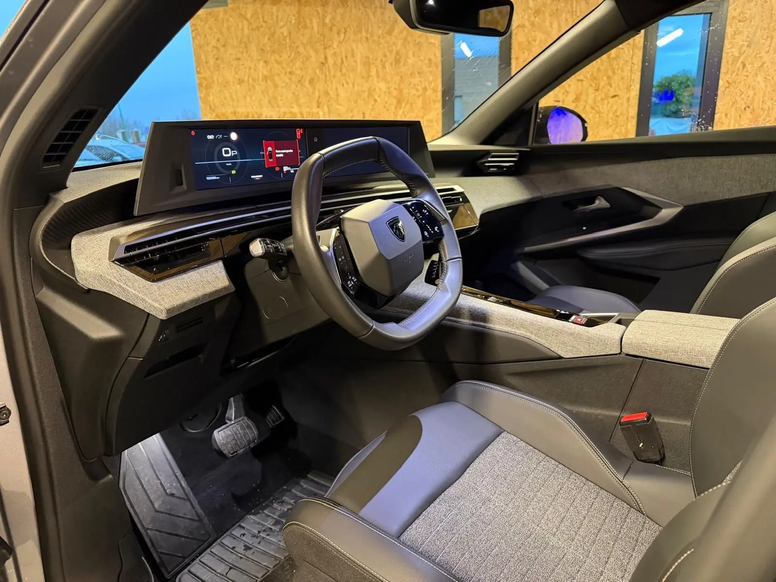 Vue intérieure côté conducteur du Peugeot 3008 gris 2025, mettant en valeur le volant compact et l'écran numérique large.