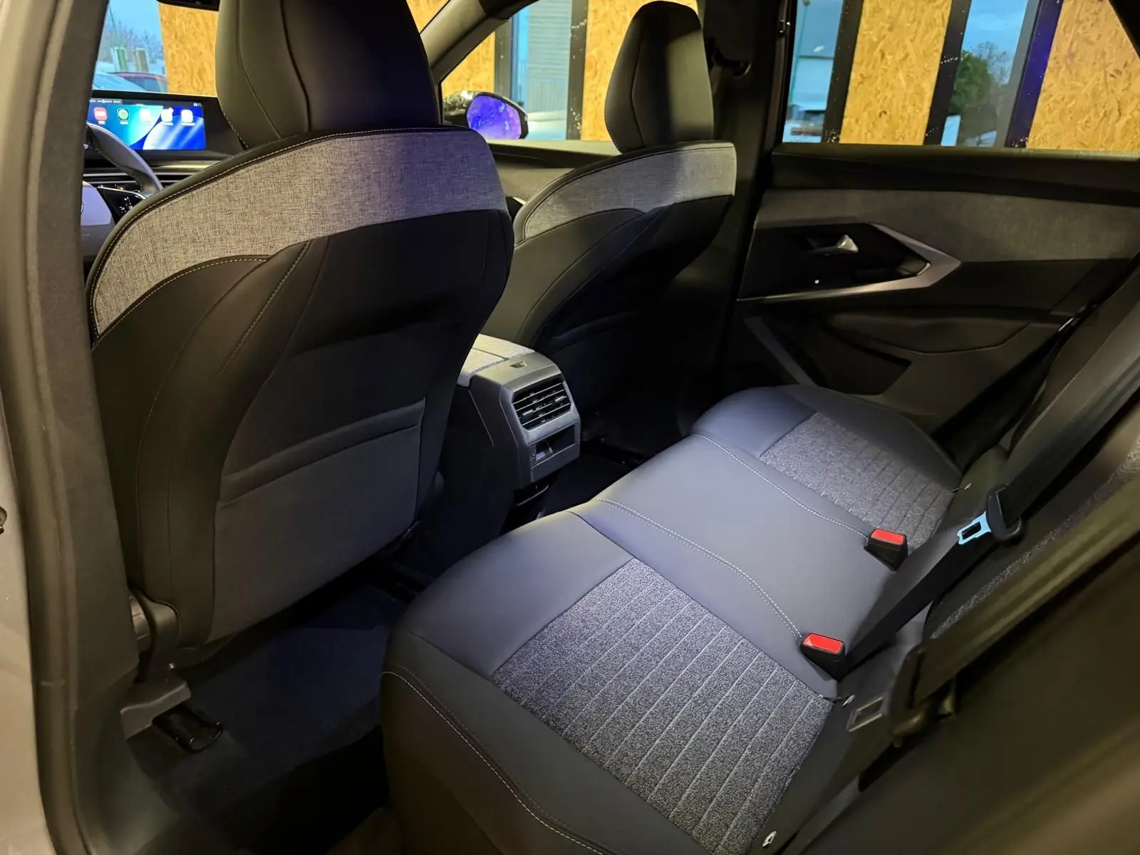 Vue intérieure arrière droite du Peugeot 3008 1.2 Hybrid 136 Allure, sièges tissu noir et gris, ambiance moderne et lumineuse.