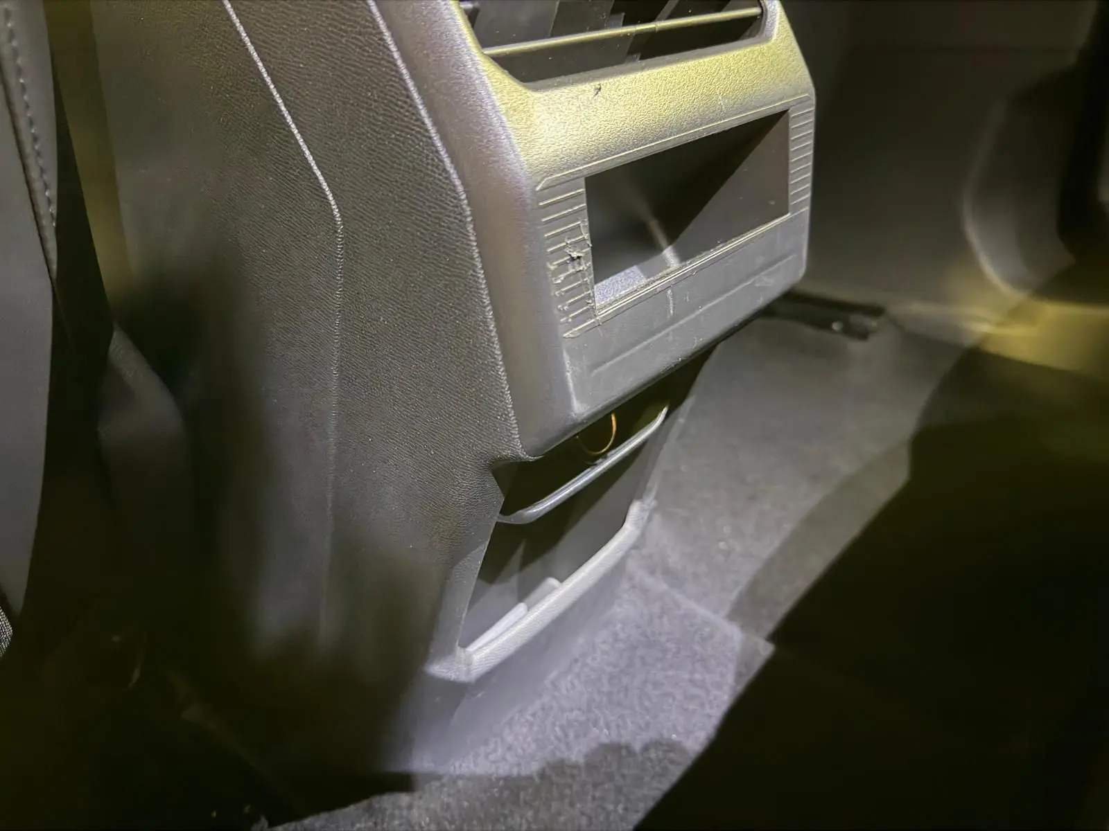 Détail de la console arrière noire du Peugeot 3008 1.2 Hybrid 136 Allure, avec rangement et prise visible.