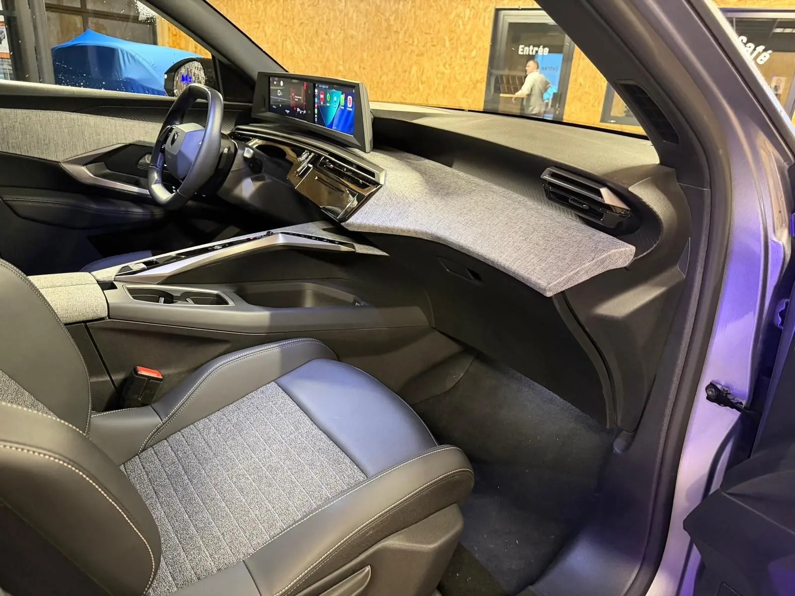 Vue intérieure côté passager du Peugeot 3008 1.2 Hybrid 136 Allure gris, avec tableau de bord moderne et sellerie tissu noir et gris.