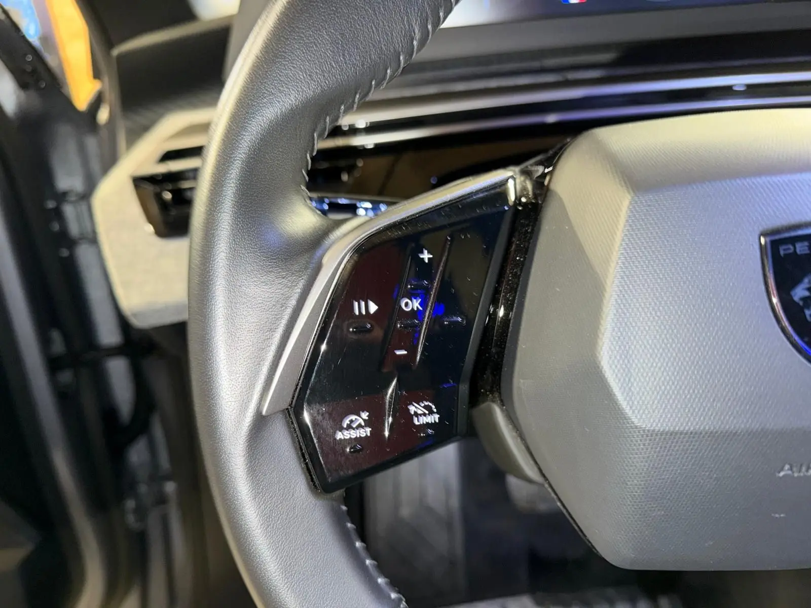 Gros plan sur les commandes gauche du volant gris du Peugeot 3008 1.2 Hybrid 136 Allure, intérieur noir.