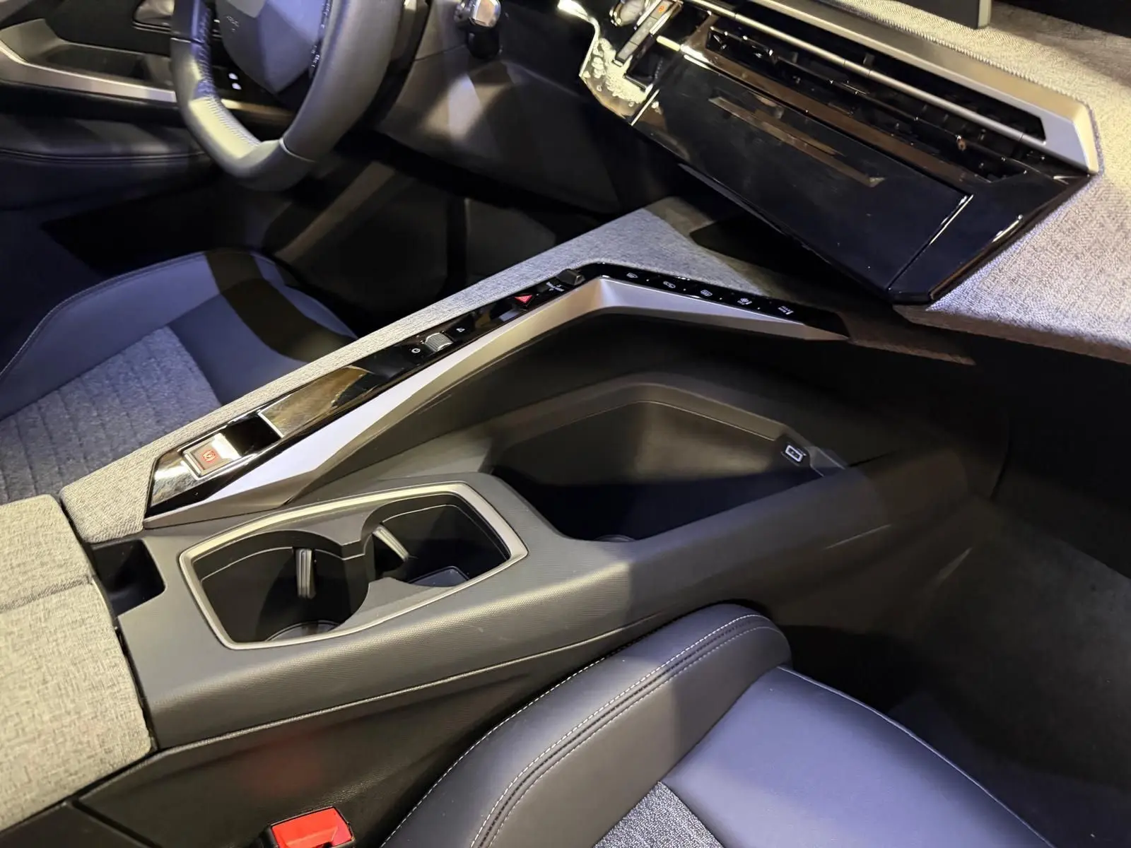 Vue intérieure côté passager du Peugeot 3008 1.2 Hybrid 136 Allure gris, avec console centrale et sièges tissu noir et gris.