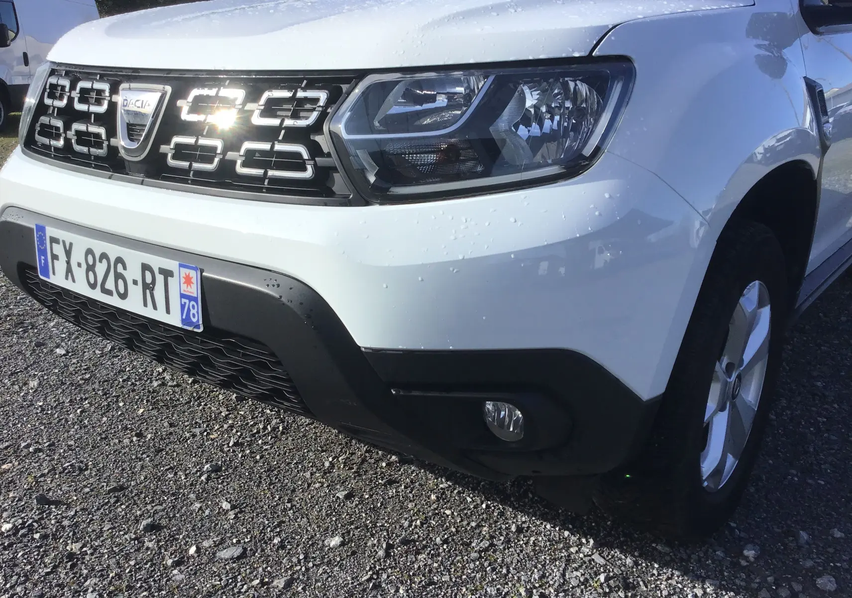 Vue avant droite d’un Dacia Duster blanc 2021 avec calandre noire distinctive et plaque d’immatriculation française.