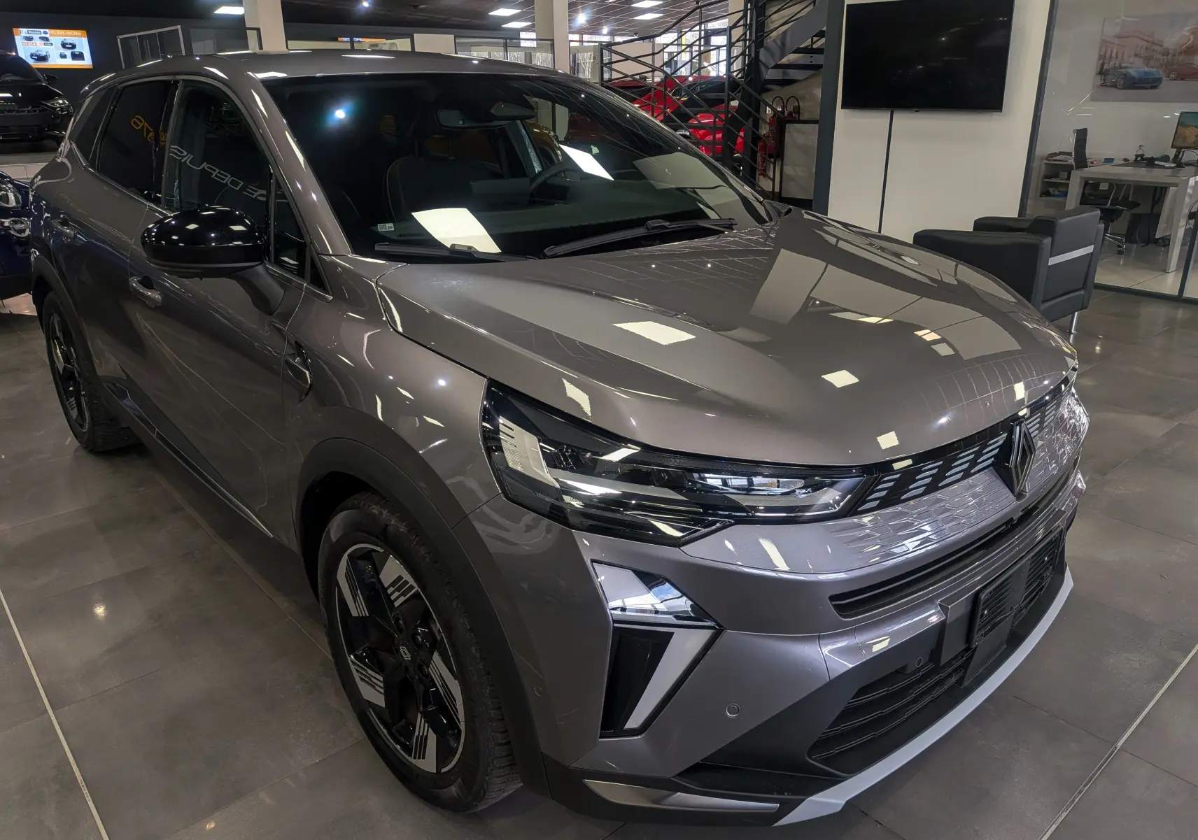 Renault Symbioz E-TECH gris Cassiopé en 3/4 avant droit, avec phares LED et jantes bicolores noires.