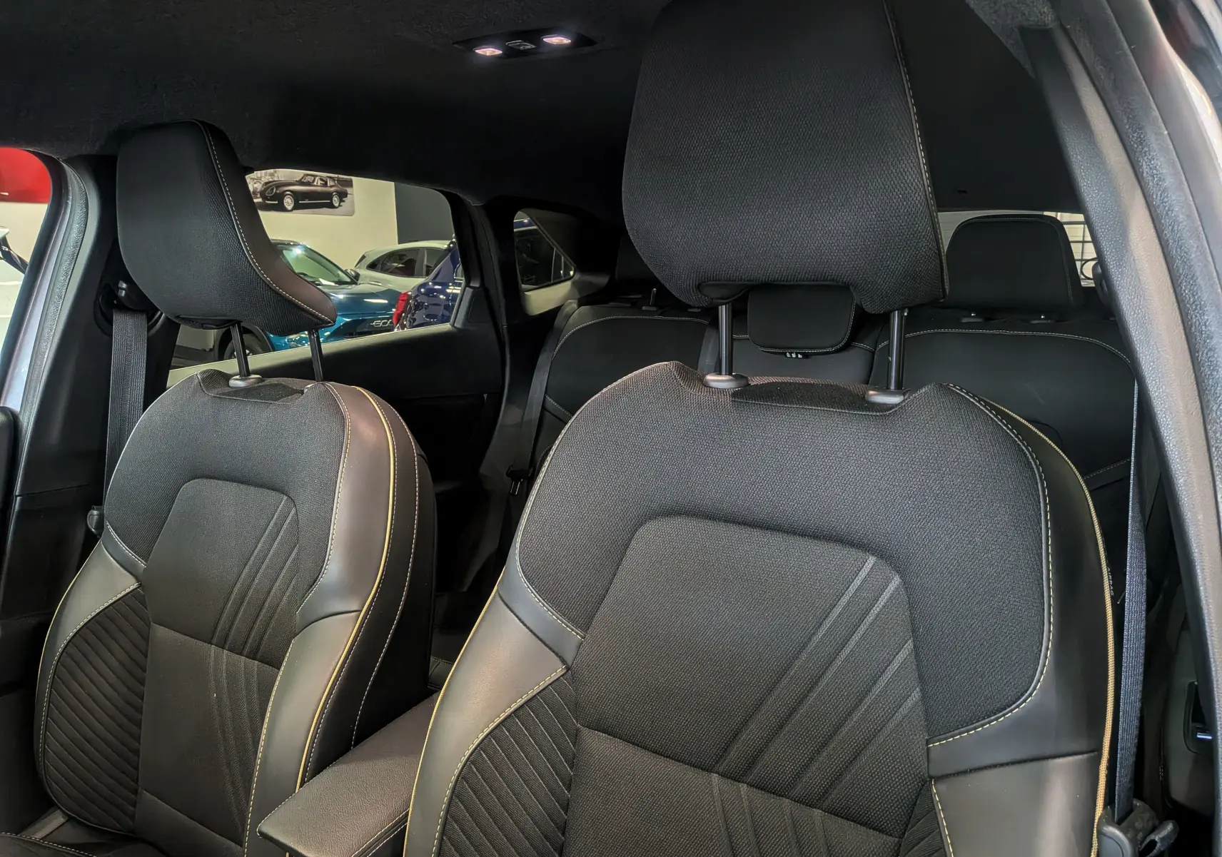 Vue intérieure rapprochée des sièges avant en tissu et cuir noir avec surpiqûres contrastantes dans une Renault Symbioz Gris Cassiopé.