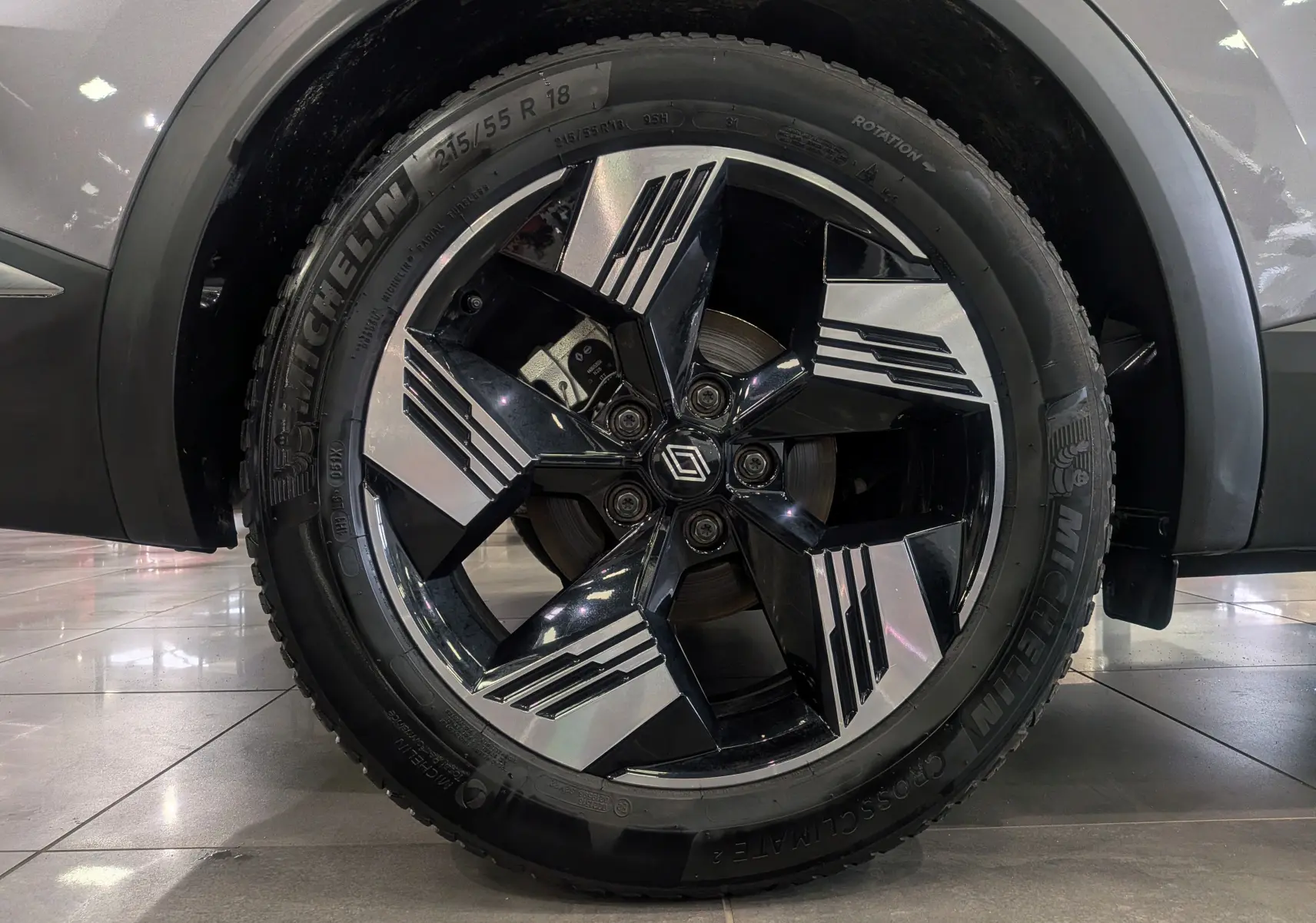 Gros plan sur la jante bi-ton noire et argentée avec logo Renault, montée sur un pneu Michelin, sur une carrosserie gris Cassiopé.