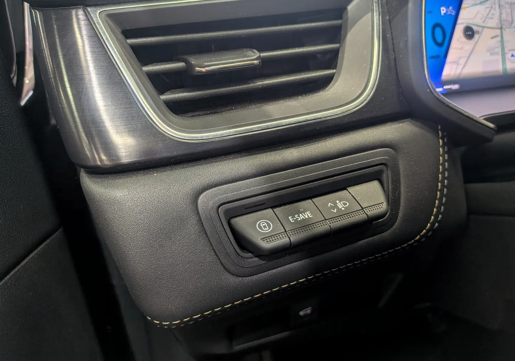 Gros plan sur les commandes à gauche du tableau de bord du Renault Symbioz gris Cassiopé, avec boutons E-SAVE et réglage phares.