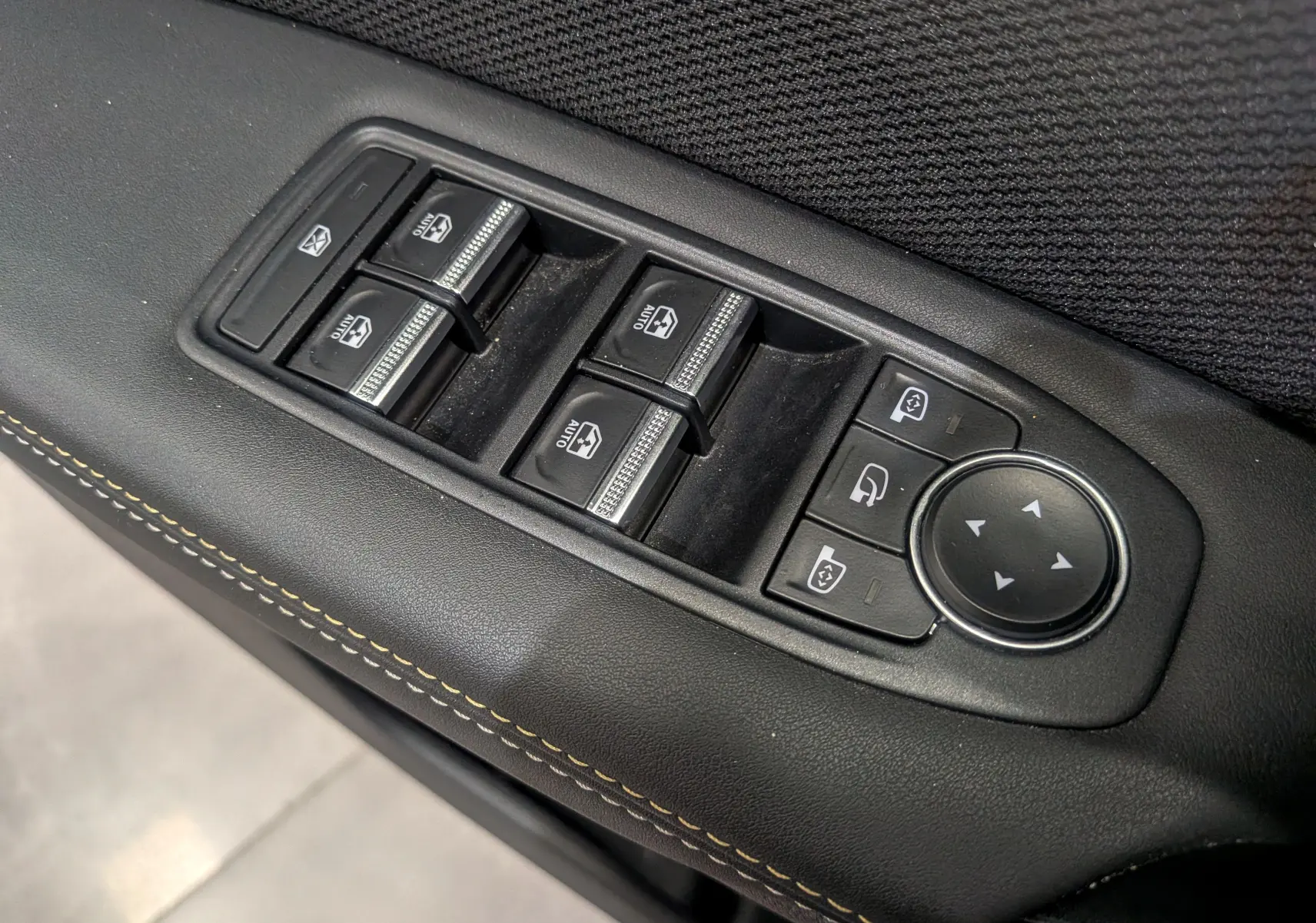 Gros plan sur les commandes de lève-vitres et rétroviseurs sur la porte intérieure noire du Renault Symbioz 2025.