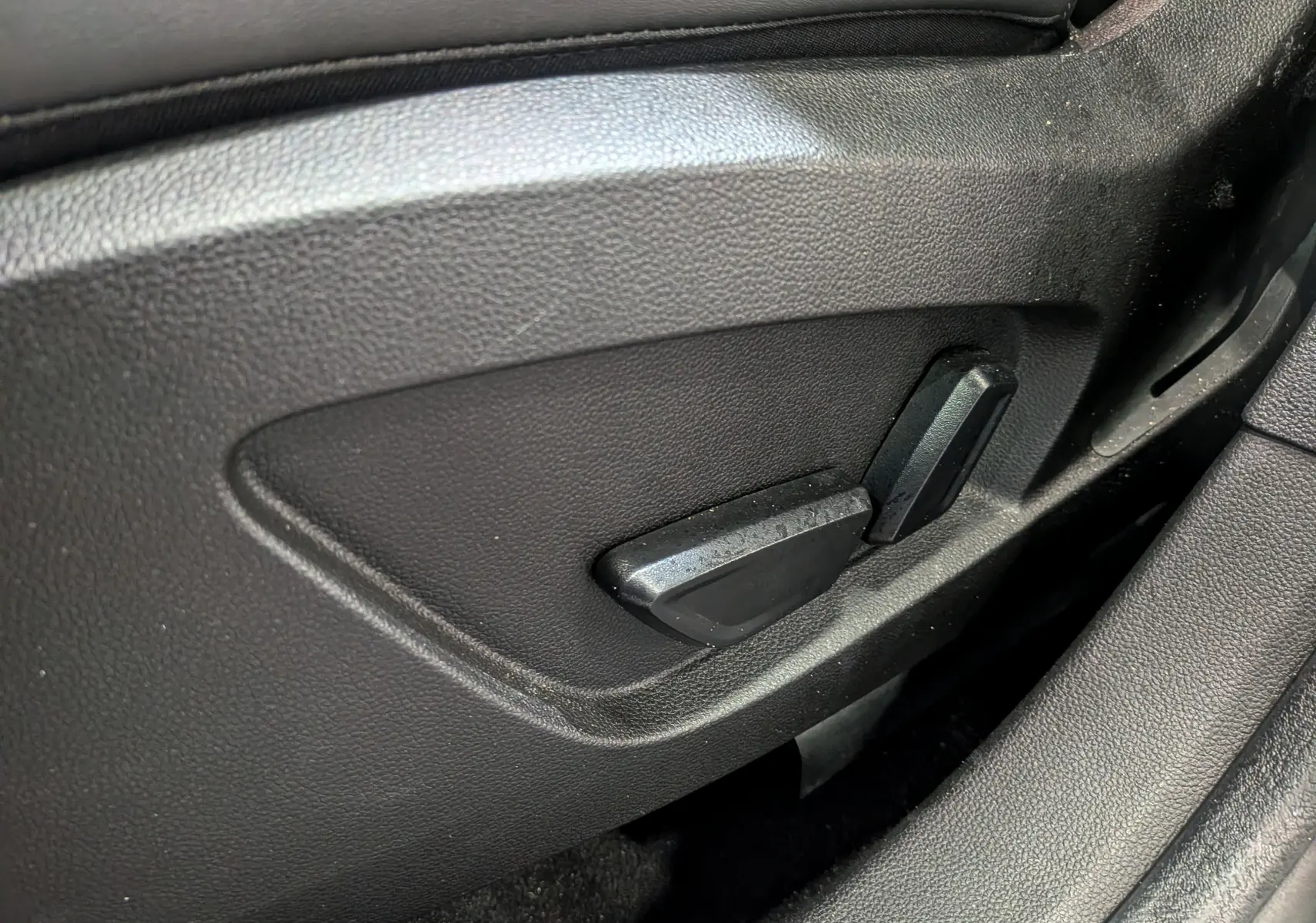 Gros plan sur les commandes de réglage électrique du siège côté gauche, intérieur noir du Renault Symbioz gris Cassiopé.