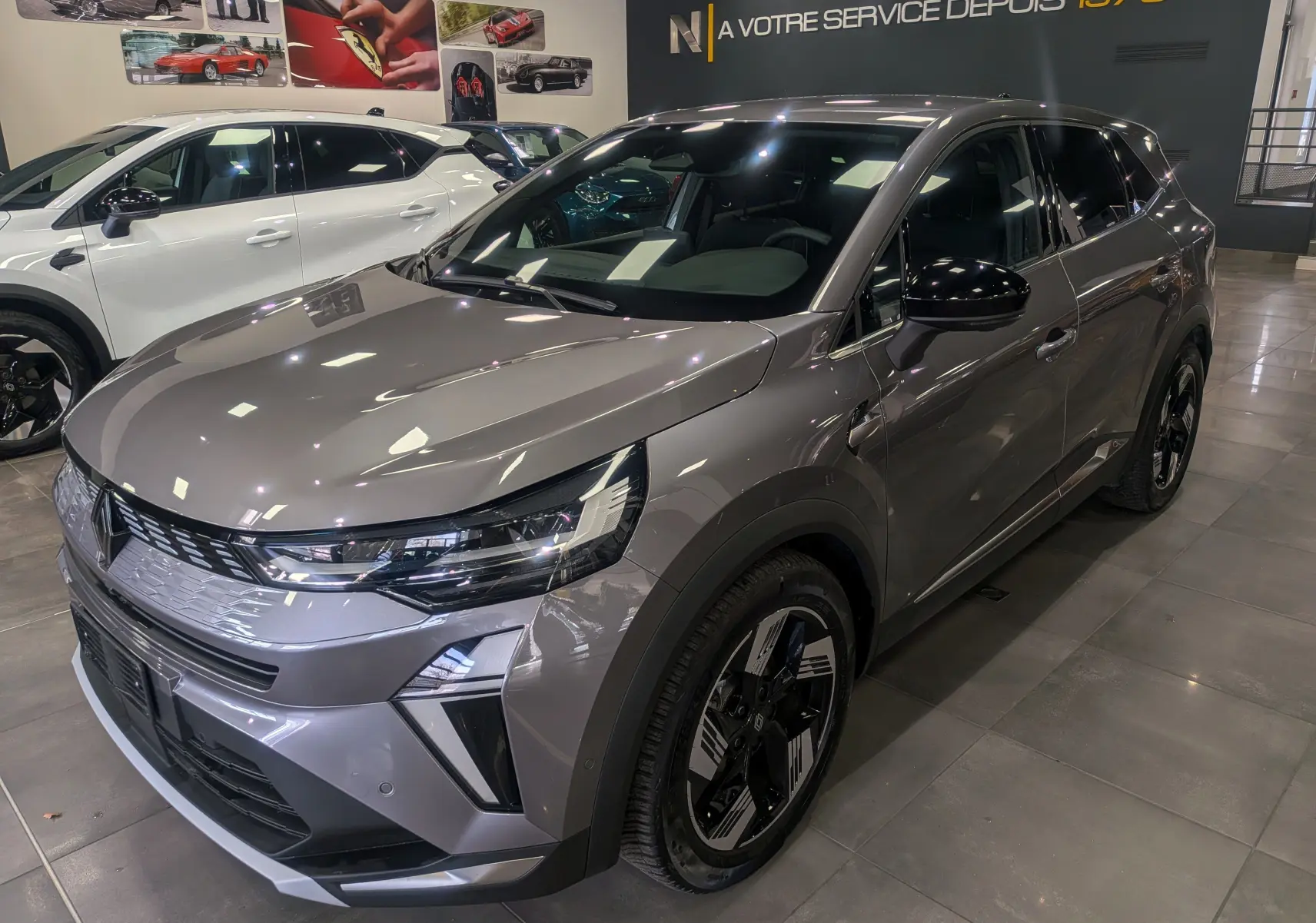 Renault Symbioz E-Tech Full Hybrid gris Cassiopé, vue 3/4 avant droit, jantes noires et détails lumineux LED.