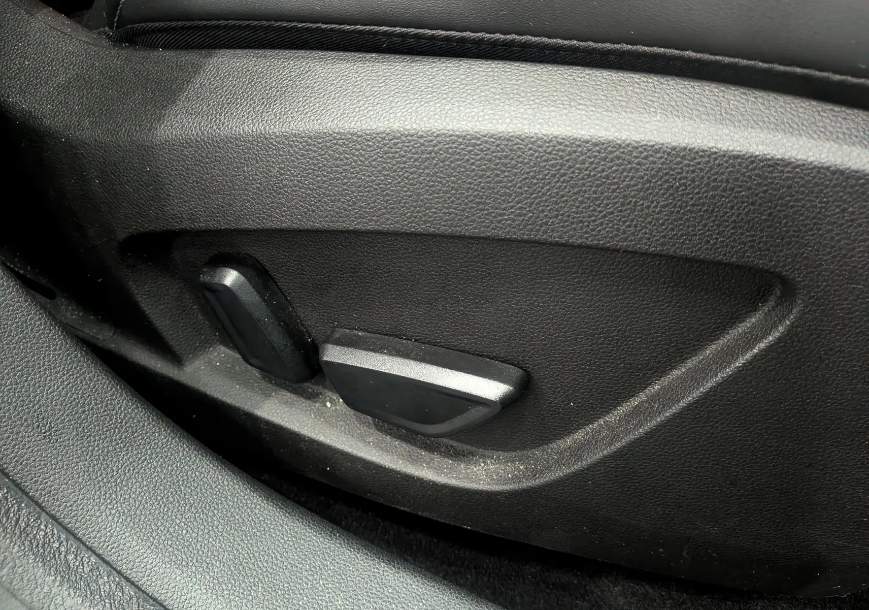 Gros plan sur les commandes électriques de réglage du siège côté gauche, intérieur noir du Renault Symbioz Gris Cassiopé.