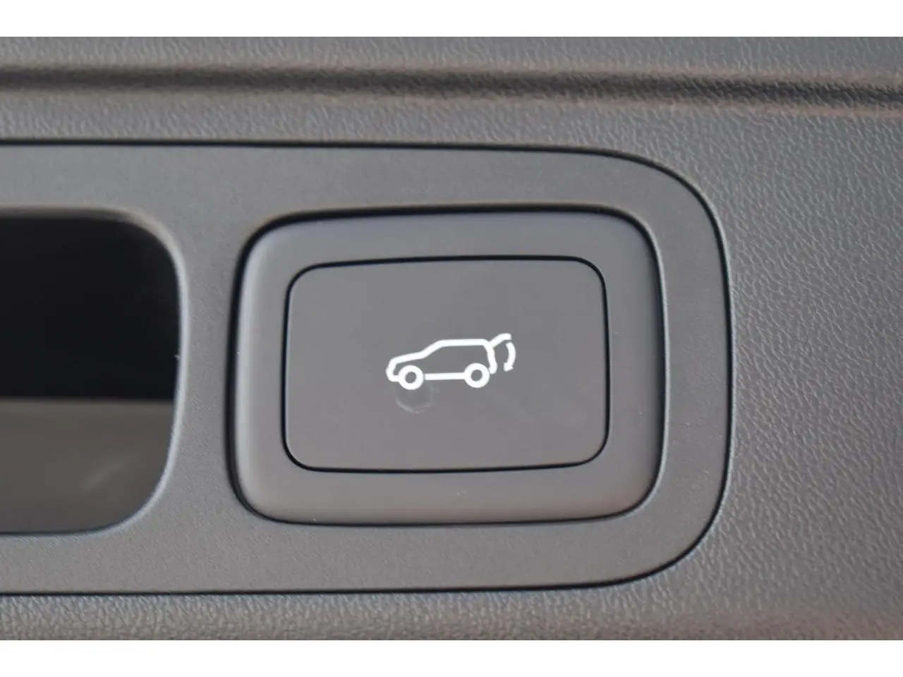 Bouton intérieur noir avec pictogramme blanc d'ouverture du hayon sur MG Motor EHS hybride 2026.