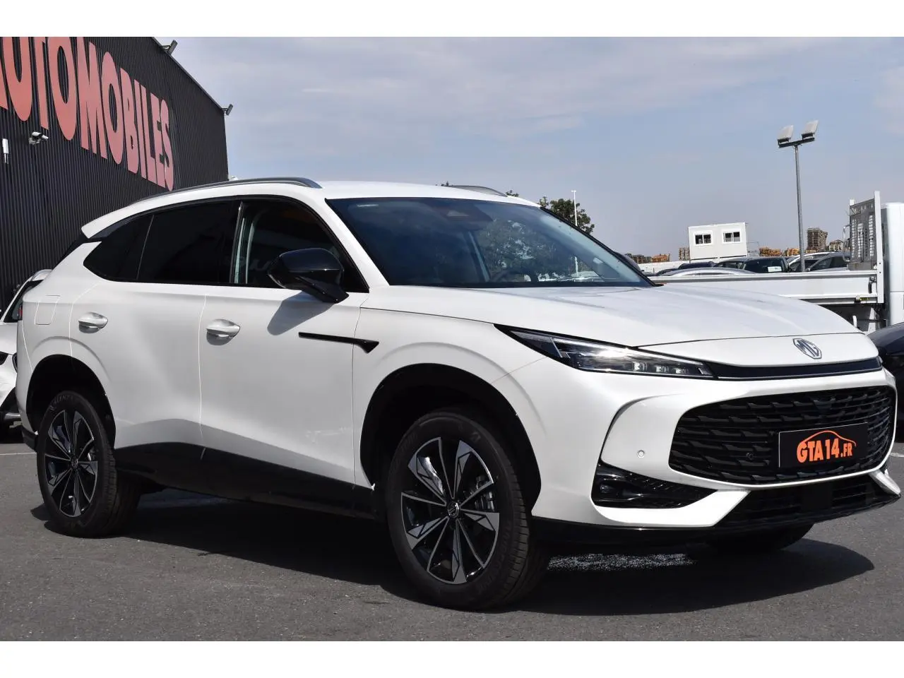 MG Motor EHS blanc en 3/4 avant droit avec jantes alliage noires et calandre noire distinctive.
