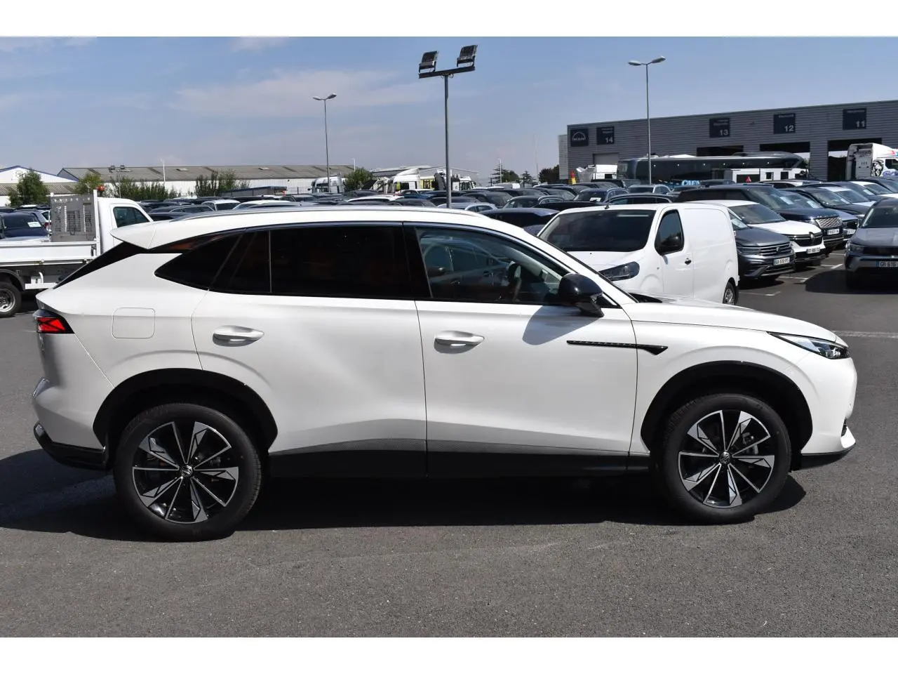 Vue profil droit du SUV MG EHS blanc métallisé, avec jantes alliage noires et vitres arrière surteintées.