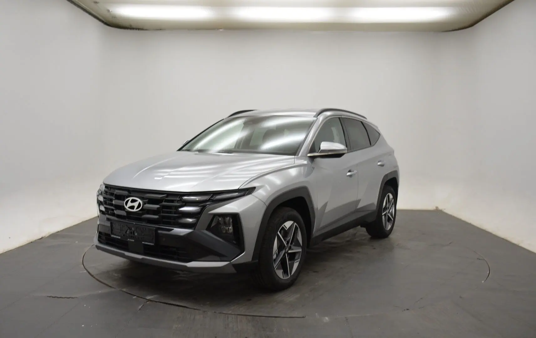 Hyundai Tucson 2025 Shimmering Silver en 3/4 avant droit, avec jantes 18 pouces et calandre noire distinctive.