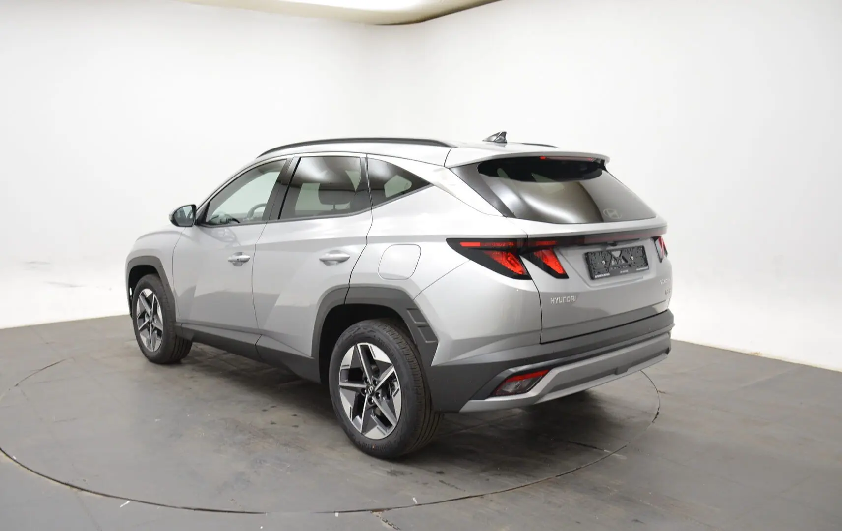 Vue 3/4 arrière droite du Hyundai Tucson 2025 hybride en gris Shimmering Silver avec jantes 18 pouces et vitres surteintées.