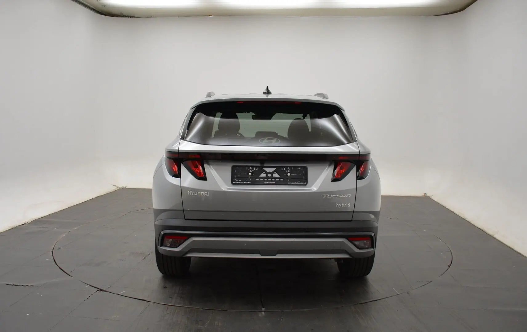 Vue arrière d'un Hyundai Tucson hybride 2025 en Shimmering Silver avec feux arrière LED distinctifs.