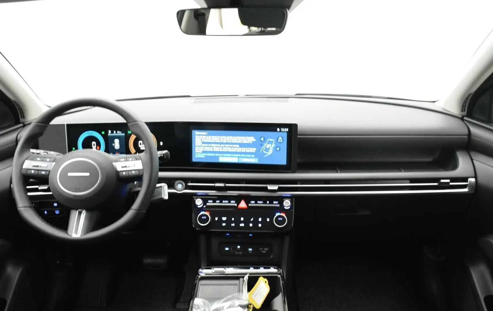 Vue intérieure avant du Hyundai Tucson 2025, tableau de bord noir avec écran tactile large et volant multifonction.