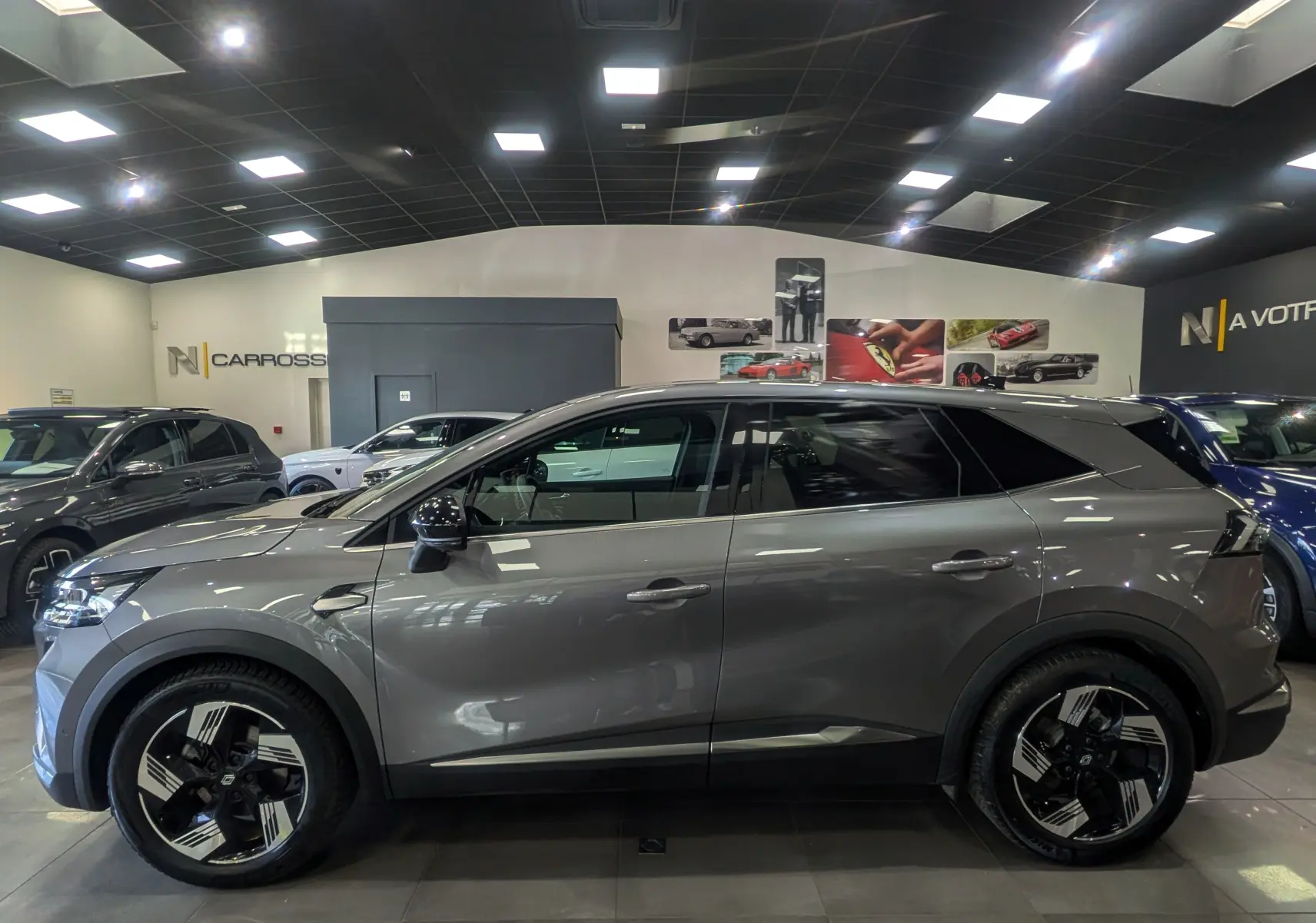 Vue de profil côté gauche du Renault SYMBIOZ gris Cassiopé, soulignant ses jantes noires et son design hybride moderne.