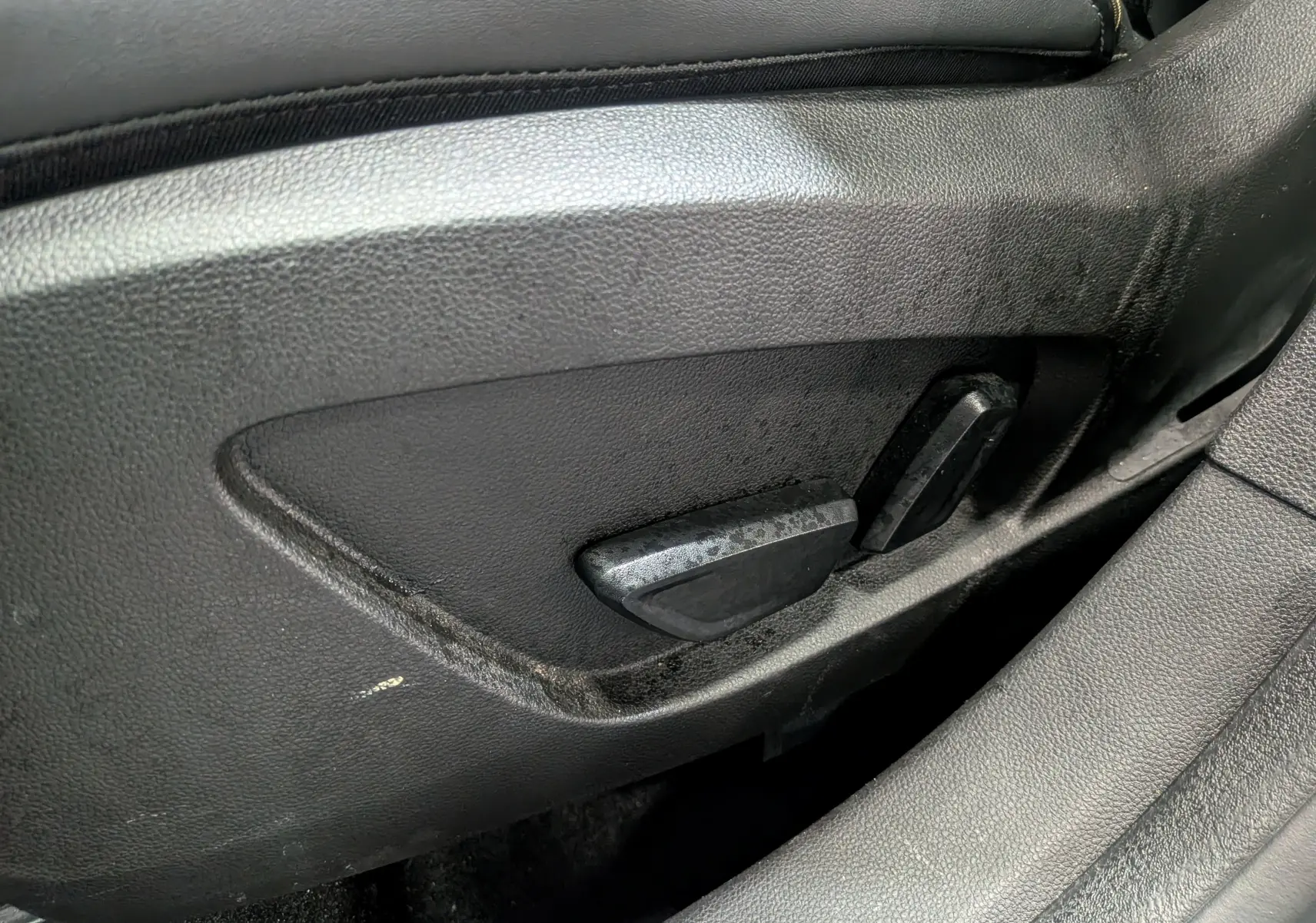 Gros plan sur les commandes de réglage électrique du siège côté gauche d'une Renault Symbioz gris Cassiopé.