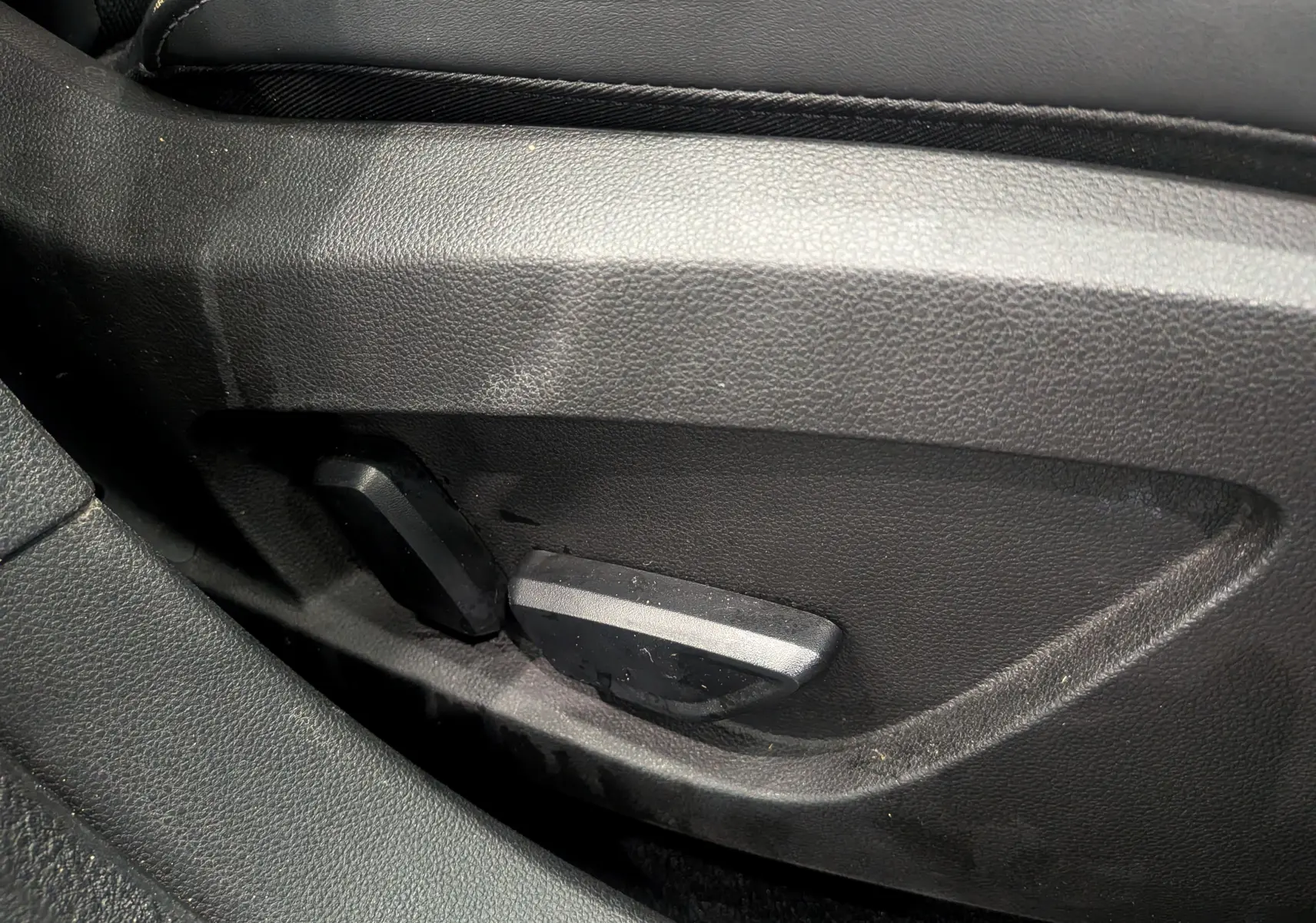 Gros plan sur les commandes de réglage électrique du siège avant en cuir noir du Renault Symbioz E-TECH 2025.