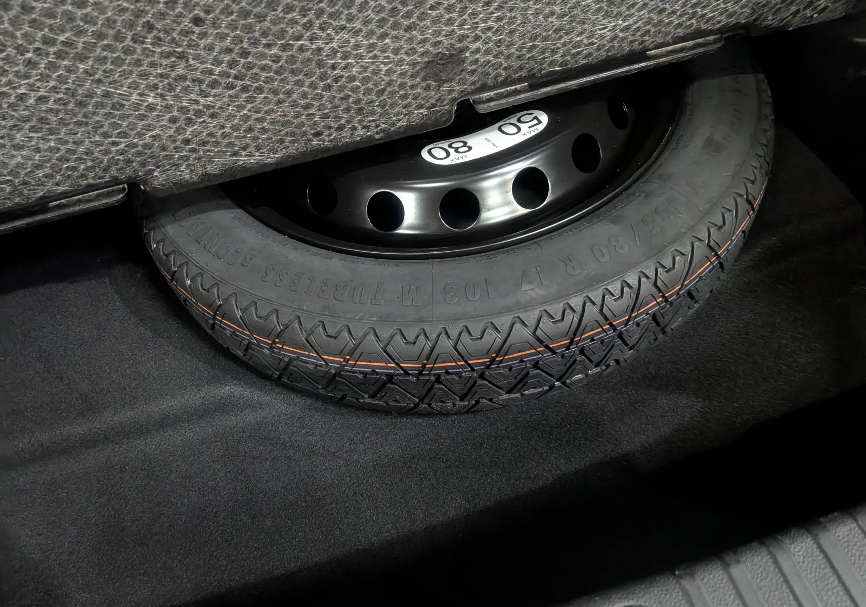 Gros plan sur la roue de secours noire dans le coffre d’un Renault SYMBIOZ gris Cassiopé, version hybride 2025.