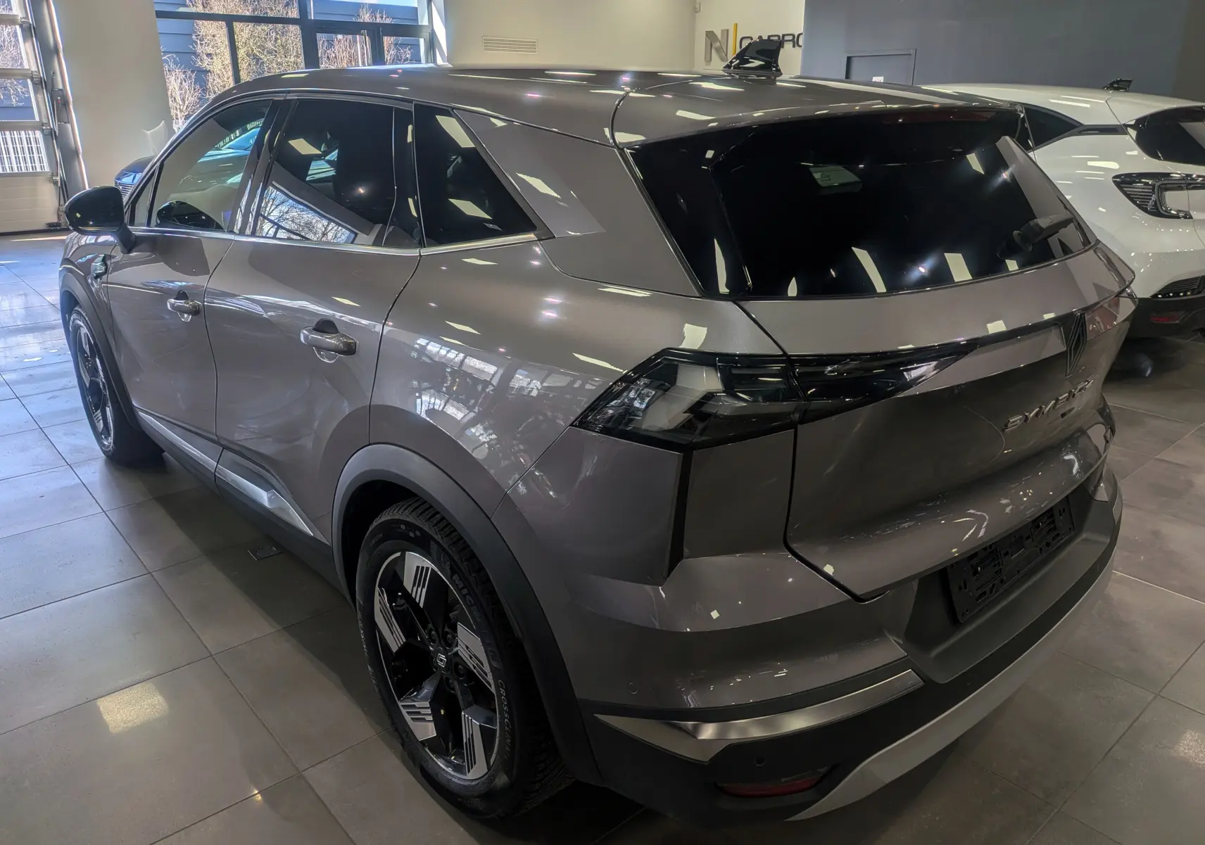 Vue 3/4 arrière droite du Renault SYMBIOZ gris Cassiopé avec feux arrière noirs et jantes bicolores.