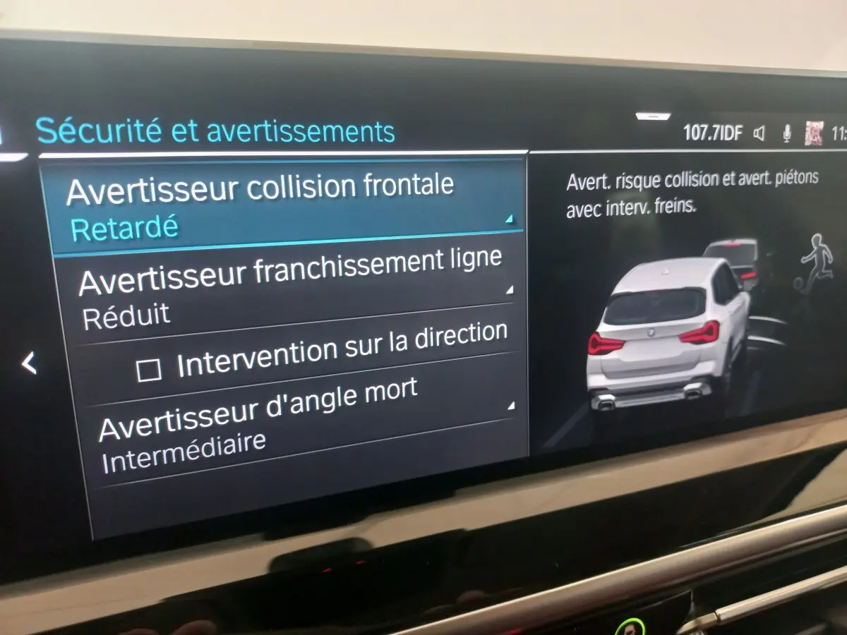 Écran tactile intérieur montrant les alertes de sécurité d’un BMW X3 blanc vu de l’arrière en illustration digitale.