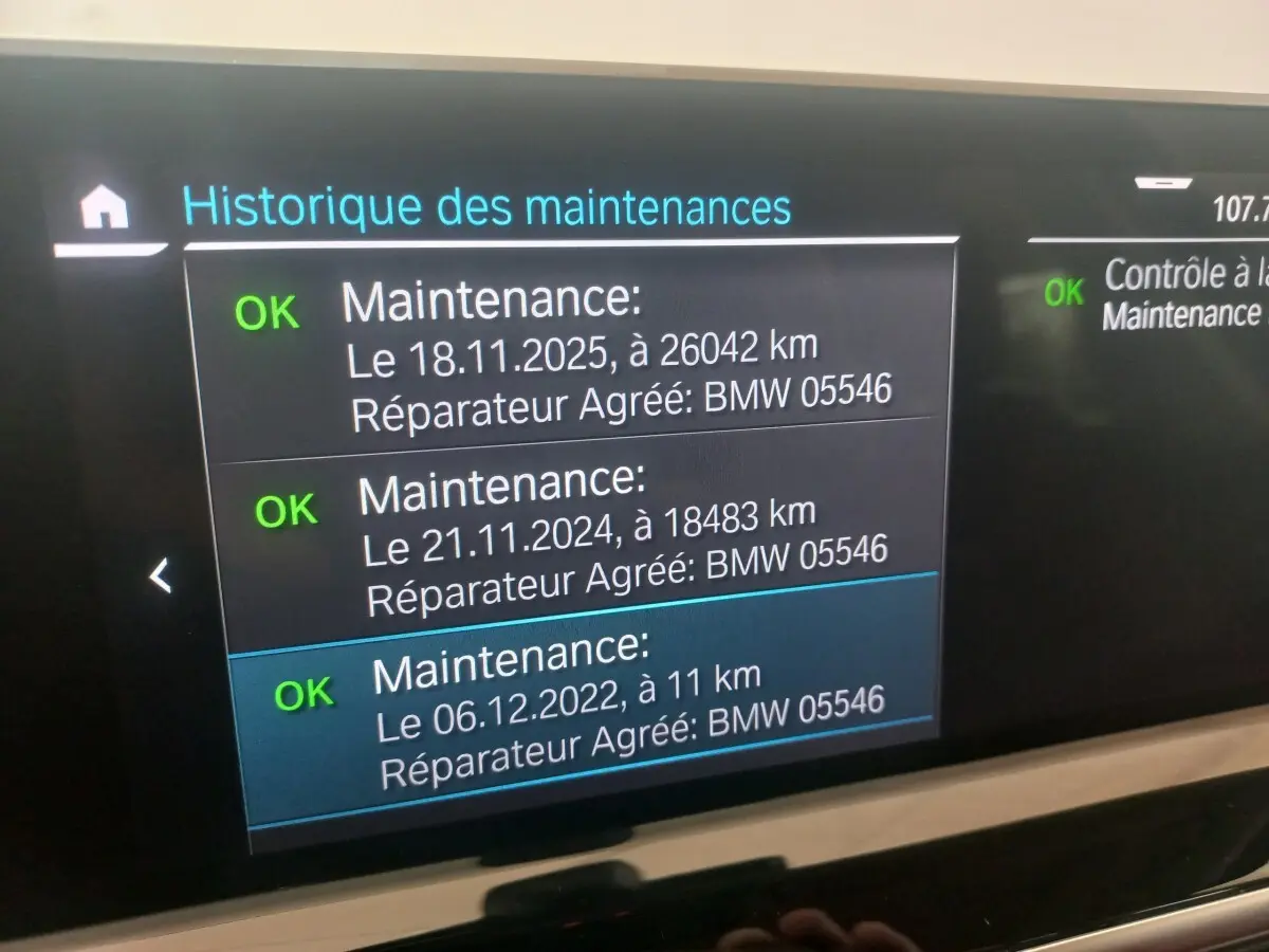 Écran central tactile affichant l'historique des maintenances du BMW X3 xDrive30e blanc, vue intérieure.