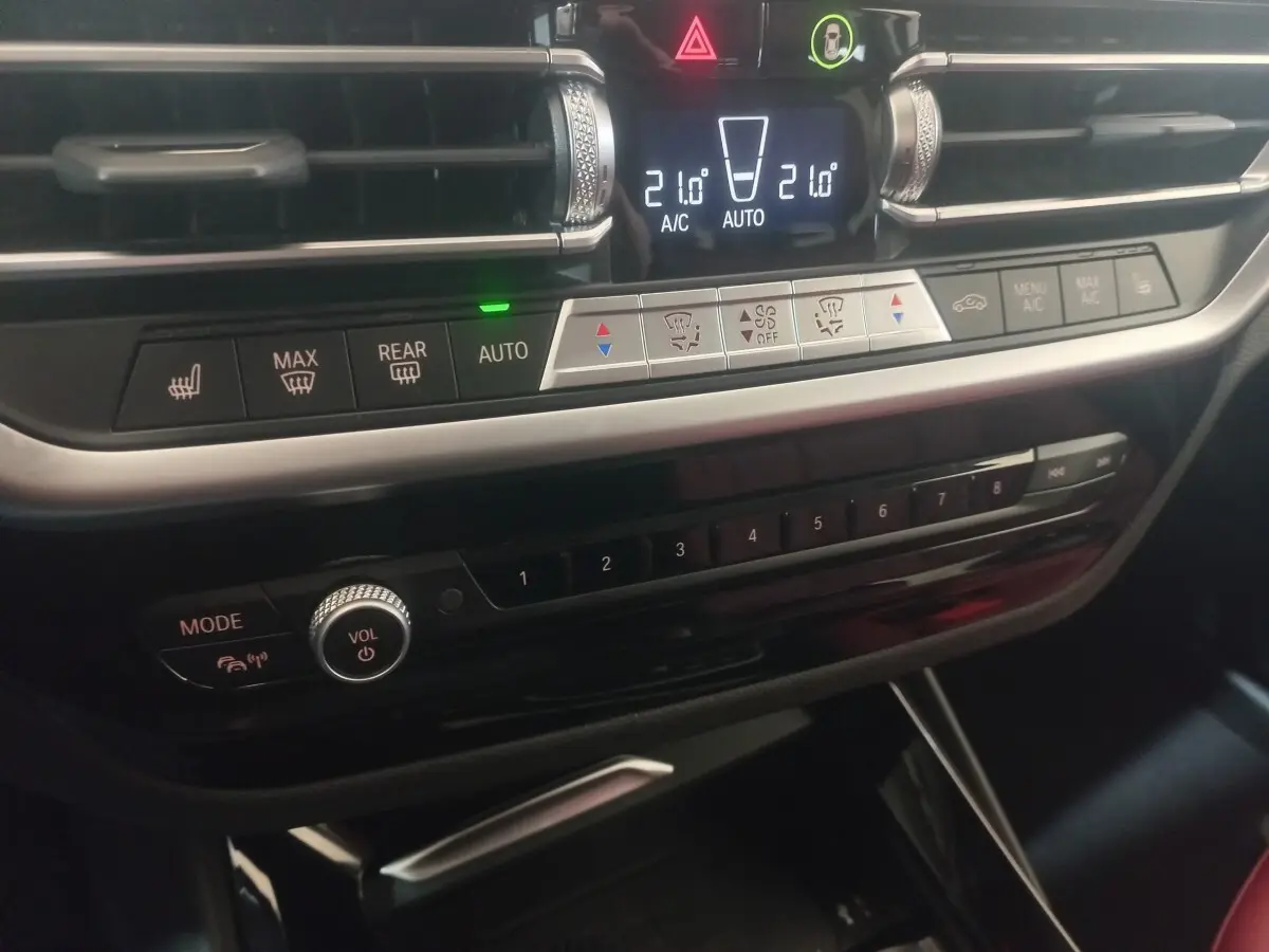 Détail du tableau de bord noir avec commandes climatisation et multimédia du BMW X3 xDrive30e blanc 2022.