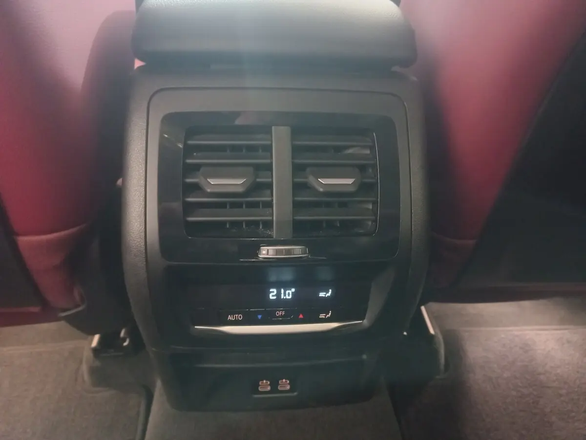 Vue rapprochée de la console arrière avec sorties d’air et commandes climatisation digitale du BMW X3 blanc 2022.