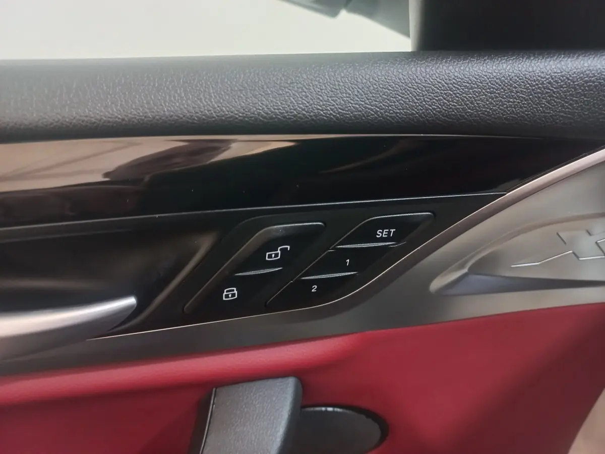 Détail de la porte intérieure côté conducteur du BMW X3 blanc 2022 avec garniture rouge et commandes de verrouillage.