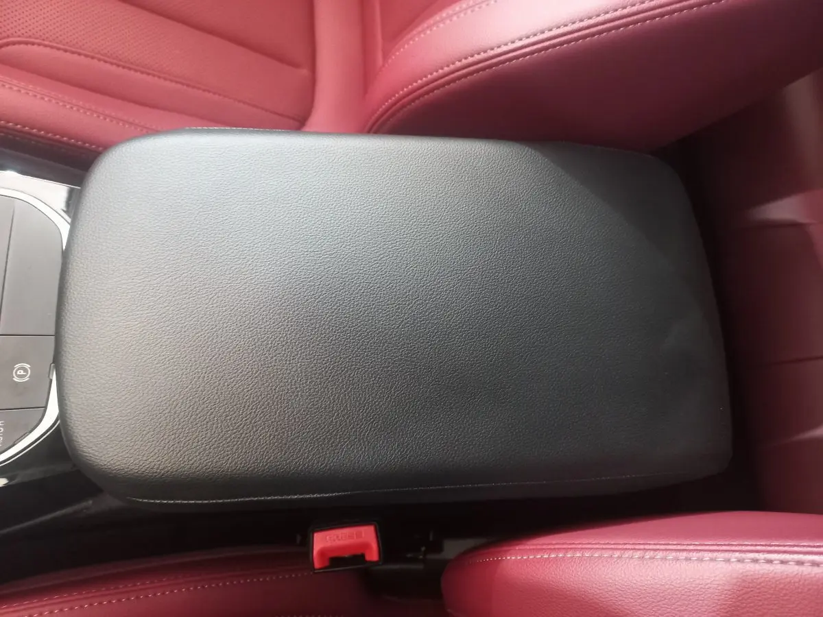 Accoudoir central noir entouré de sièges en cuir rouge dans l'habitacle du BMW X3 xDrive30e blanc 2022.