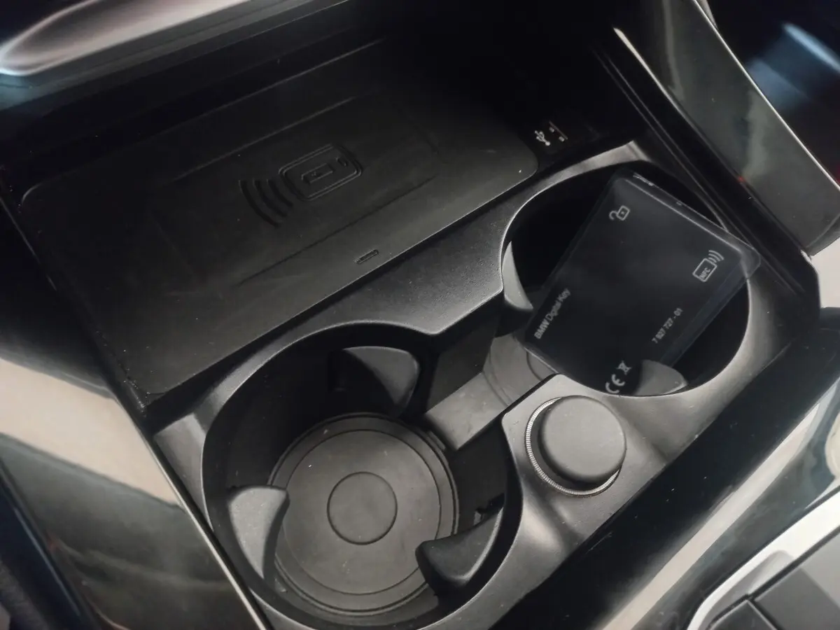 Gros plan sur la console centrale noire du BMW X3 xDrive30e 2022, avec porte-gobelets et zone de charge sans fil.