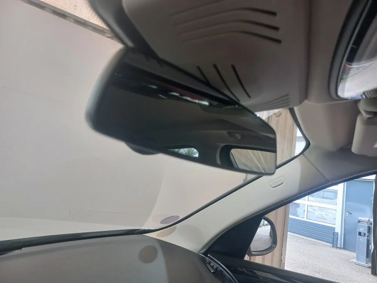Vue intérieure centrée sur le rétroviseur intérieur d’un BMW X3 blanc, avec partie du tableau de bord et vitre côté droit visible.
