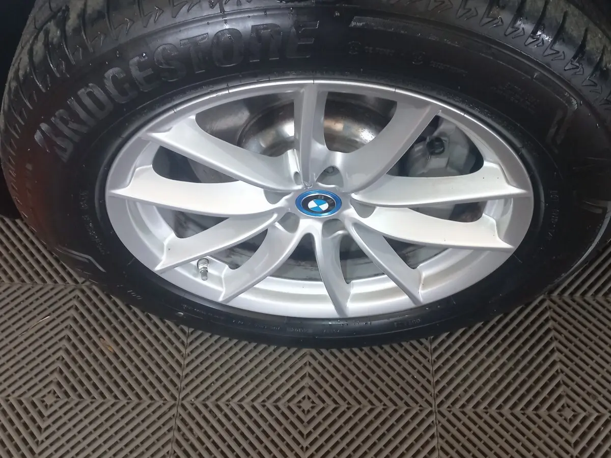 Gros plan sur la jante argentée avec logo BMW au centre, montée sur pneu Bridgestone noir.