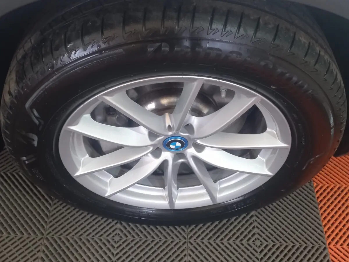 Gros plan sur la jante argentée avec logo BMW d'un BMW X3 blanc, pneu Bridgestone visible.
