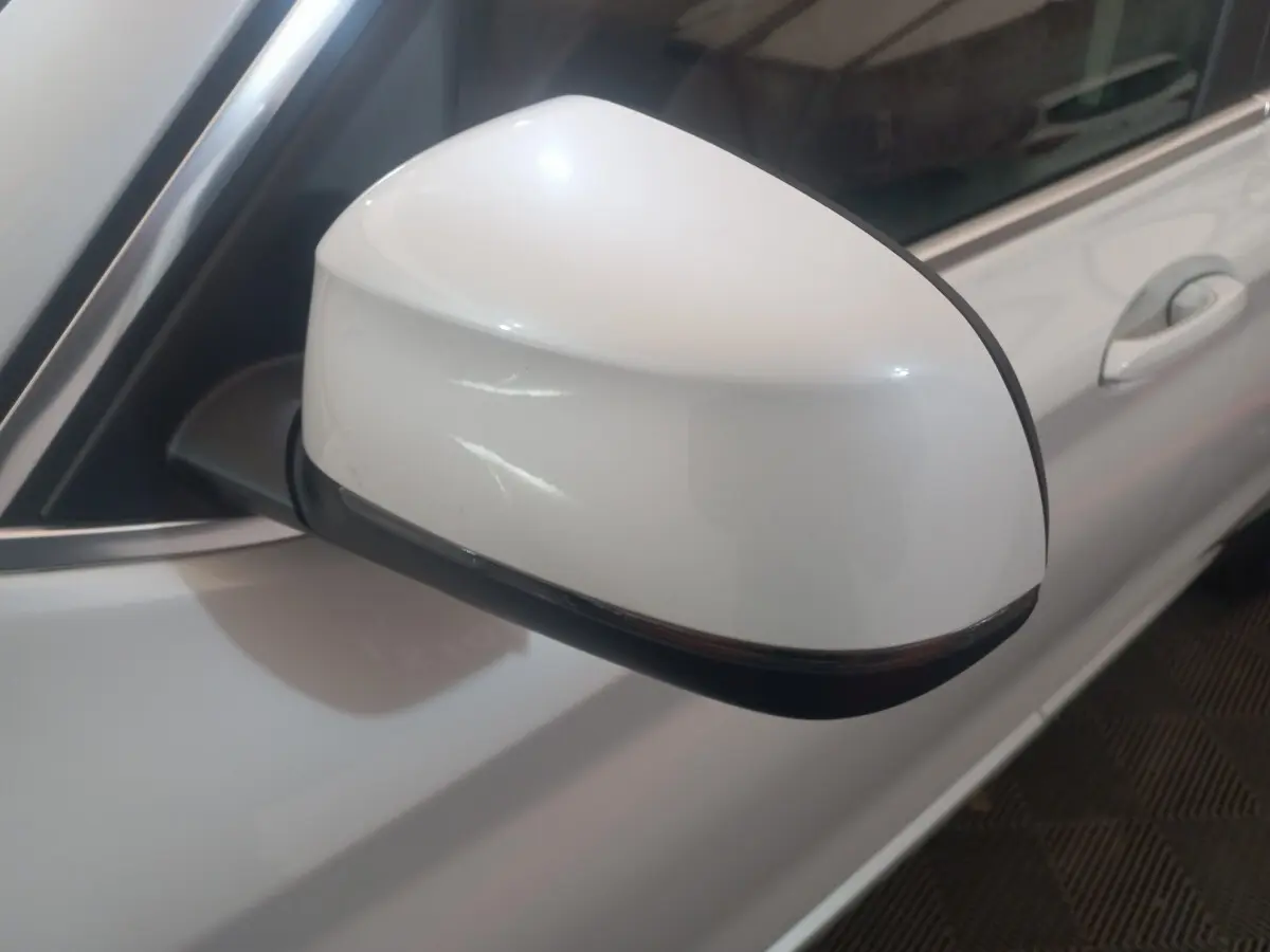 Gros plan sur le rétroviseur droit blanc du BMW X3 xDrive30e 2022, avec la portière et poignée visibles en arrière-plan.