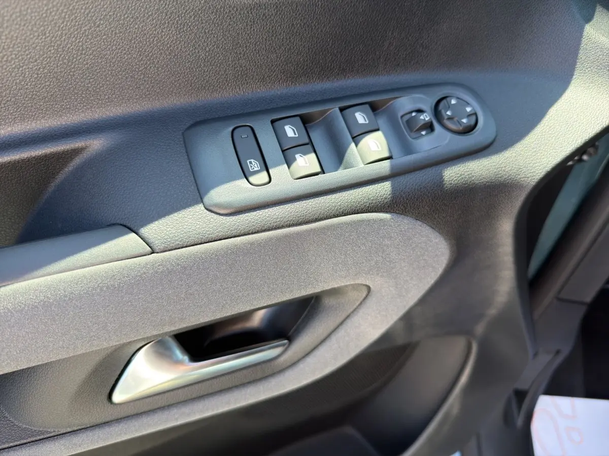 Gros plan sur la porte côté conducteur du Peugeot Rifter bleu, montrant les commandes électriques des vitres et rétroviseurs.