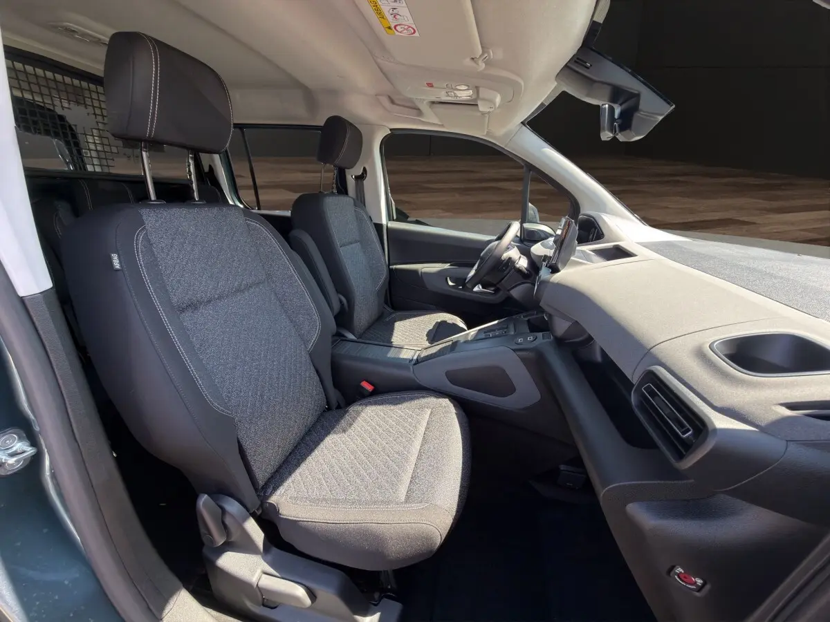 Vue intérieure côté droit du Peugeot Rifter 2026 avec sièges tissu gris et tableau de bord moderne noir.