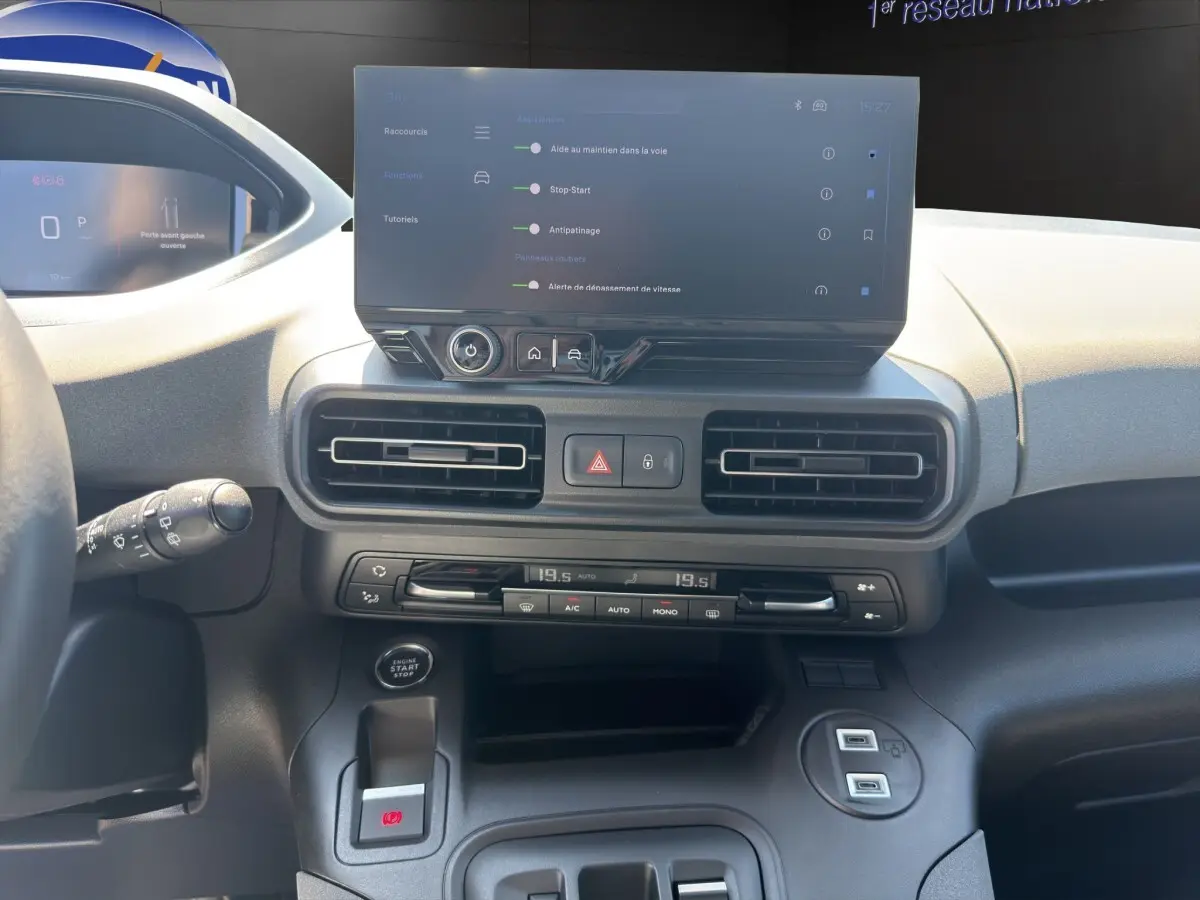 Vue intérieure du tableau de bord du Peugeot Rifter bleu 2026, avec écran tactile central et commandes climatisation visibles.