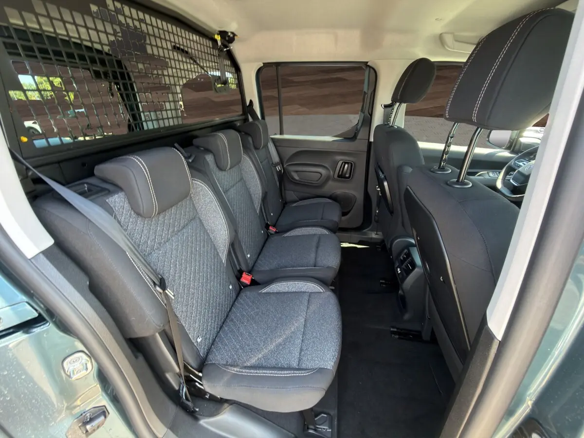 Vue intérieure côté droit sur la banquette arrière grise et noire du Peugeot Rifter bleu avec séparation grillagée.