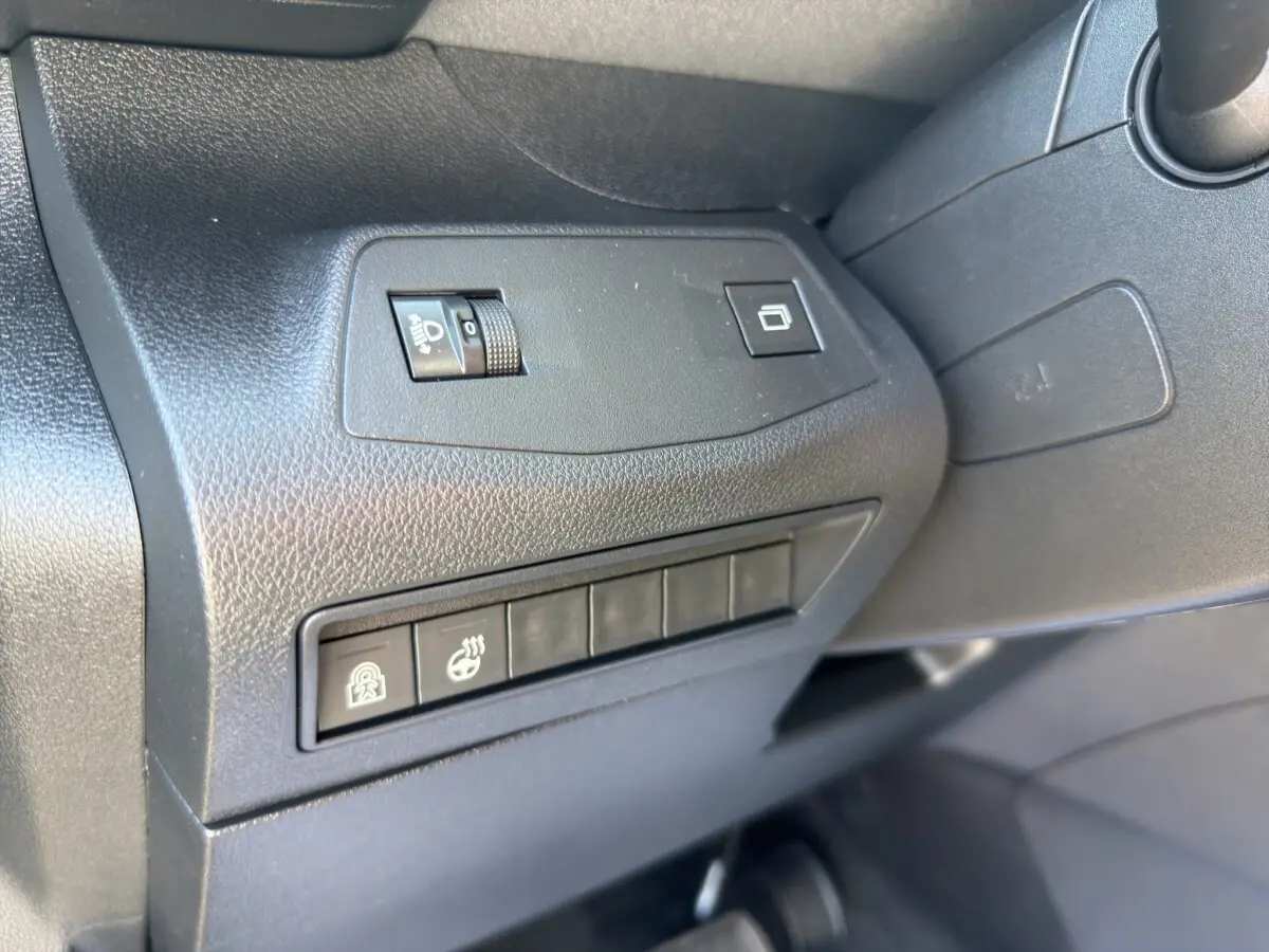 Détail intérieur côté gauche du tableau de bord noir du Peugeot Rifter avec commandes d’éclairage et boutons fonctionnels.
