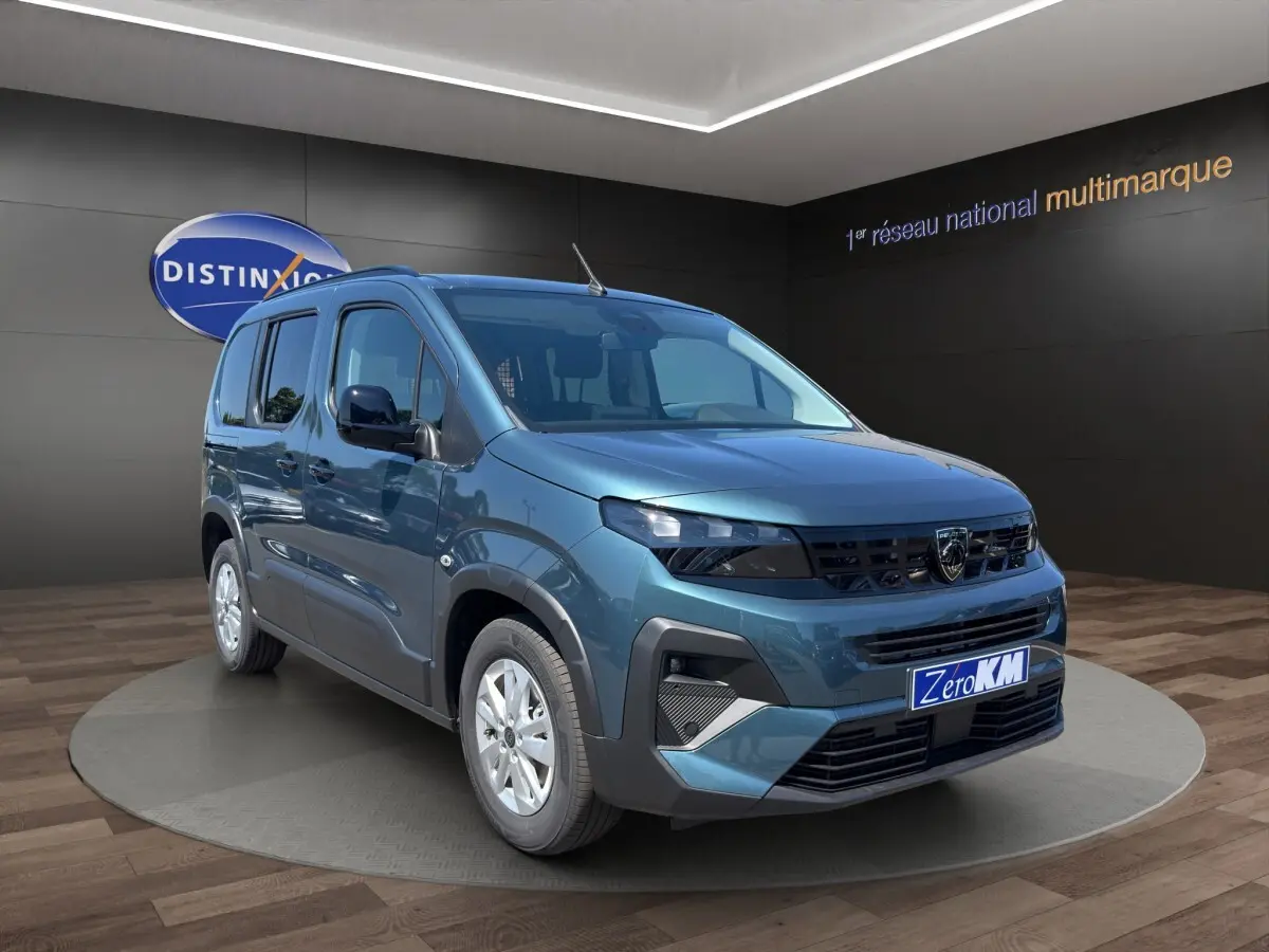 Vue 3/4 avant d'un Peugeot Rifter bleu 2026 en showroom, avec calandre noire et jantes argentées.