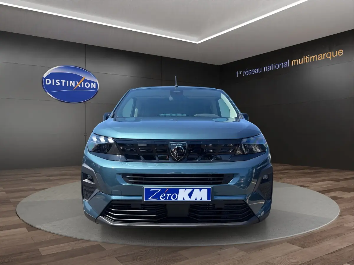 Vue frontale d'un Peugeot Rifter bleu métallisé 2026 avec calandre noire et logo lion central bien visible.