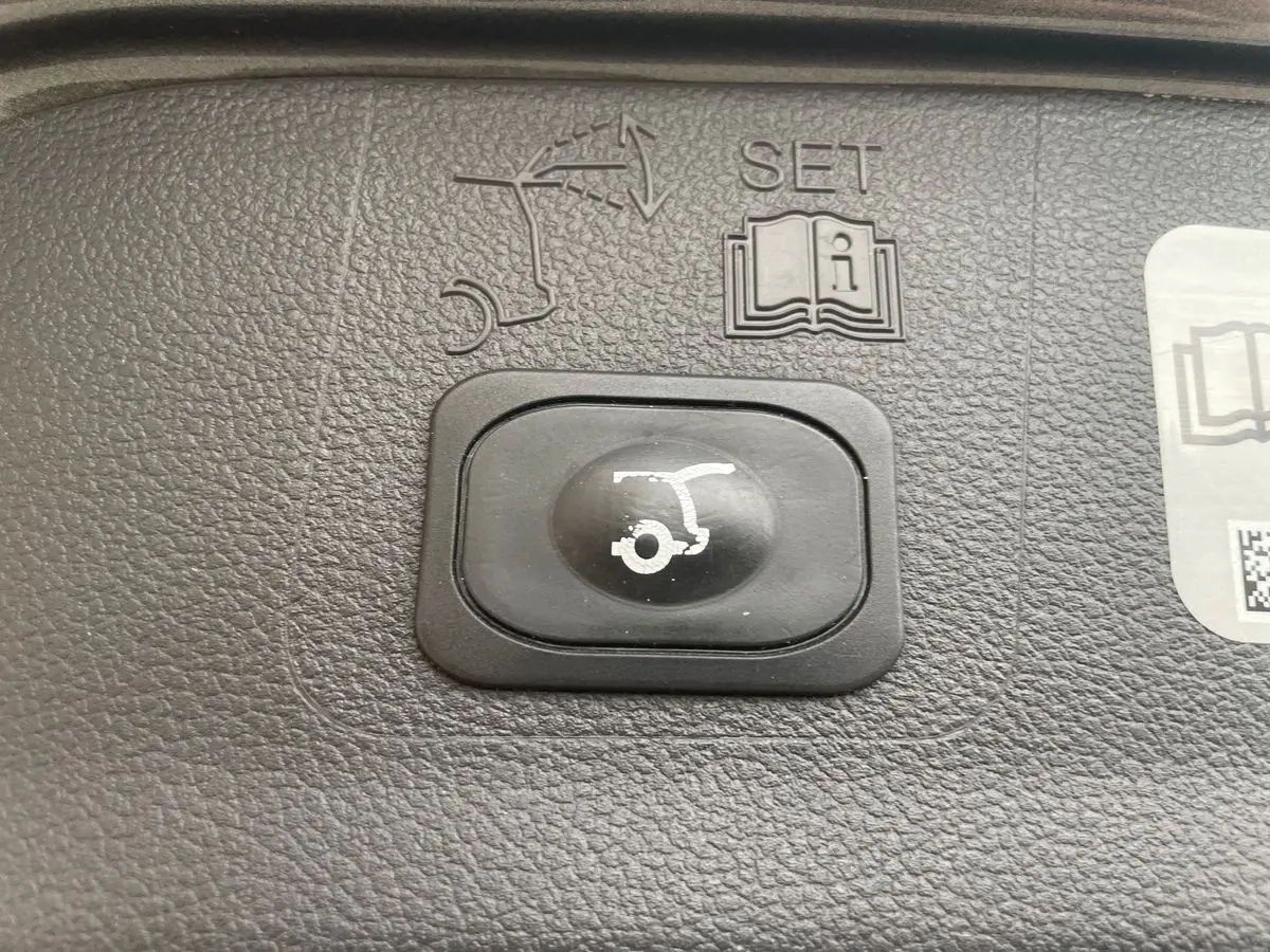 Bouton noir de commande d'ouverture du hayon sur tableau de bord texturé d'un Ford Kuga gris 2017.