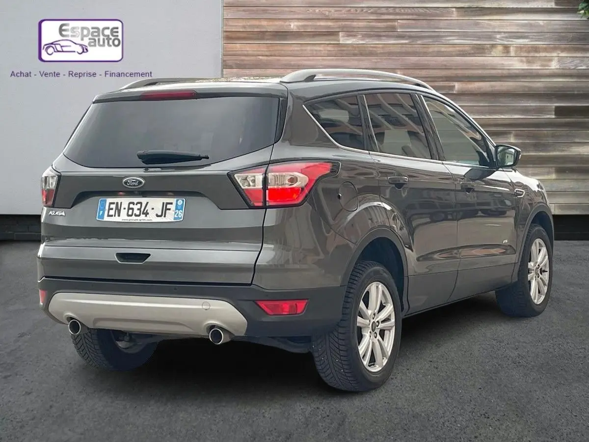 Vue 3/4 arrière droite d'un Ford Kuga gris 2017 avec double sortie d'échappement et vitres teintées.