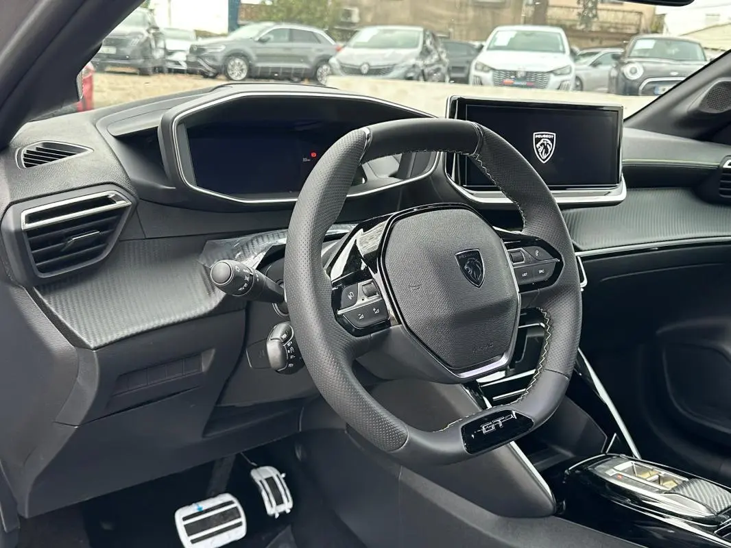 Vue intérieure du poste de conduite de la Peugeot 208 Hybrid GT 2025, avec volant compact GT et écran tactile central.